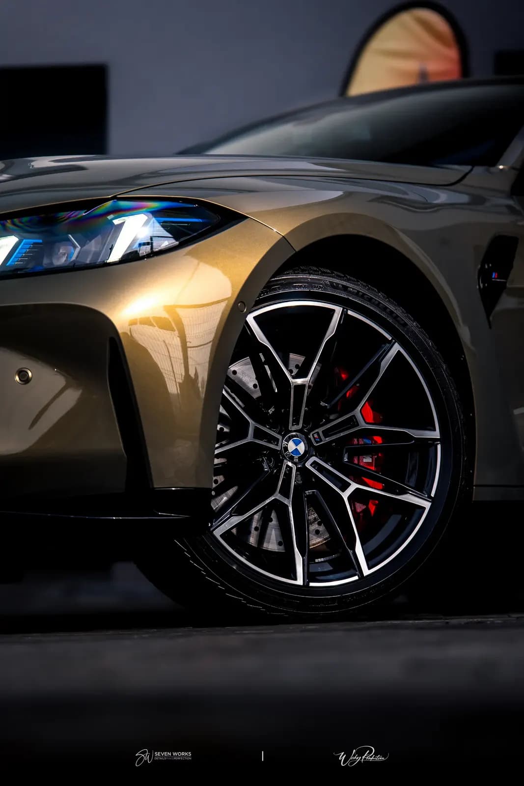 Detail předního kola BMW M4 s červenými brzdovými třmeny v dramatickém nasvícení.