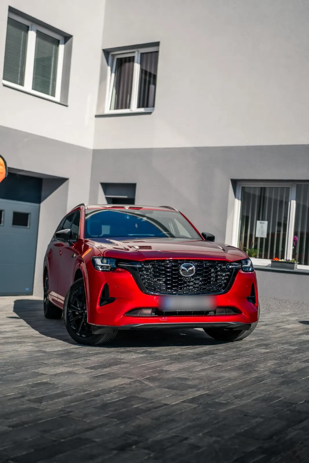 Červená Mazda CX SUV zaparkovaná před budovou provozovny, přední pohled.