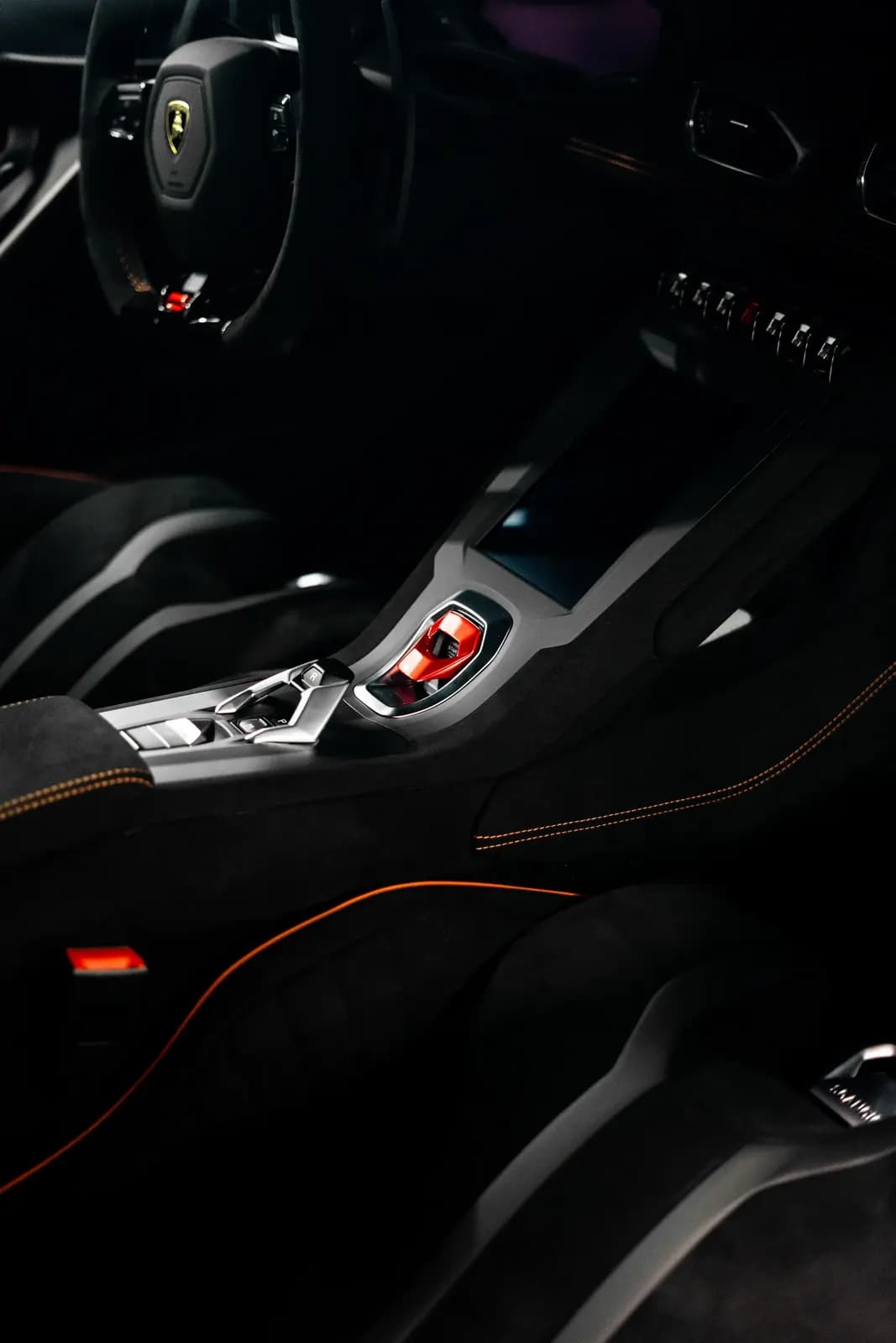 Detail středového panelu a řadicí páky v interiéru Lamborghini.