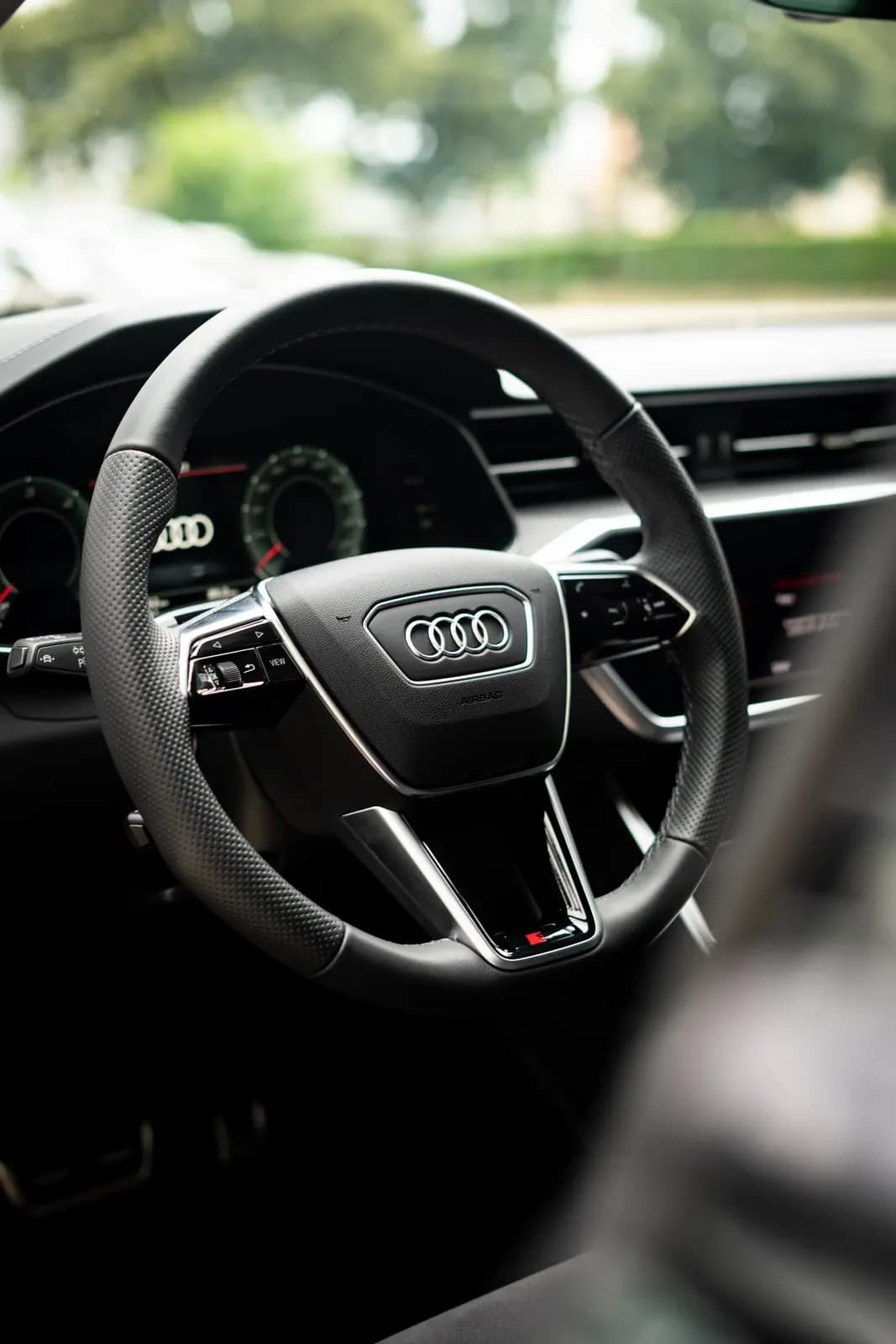Volant Audi s logem výrobce a označením S, pohled z interiéru.