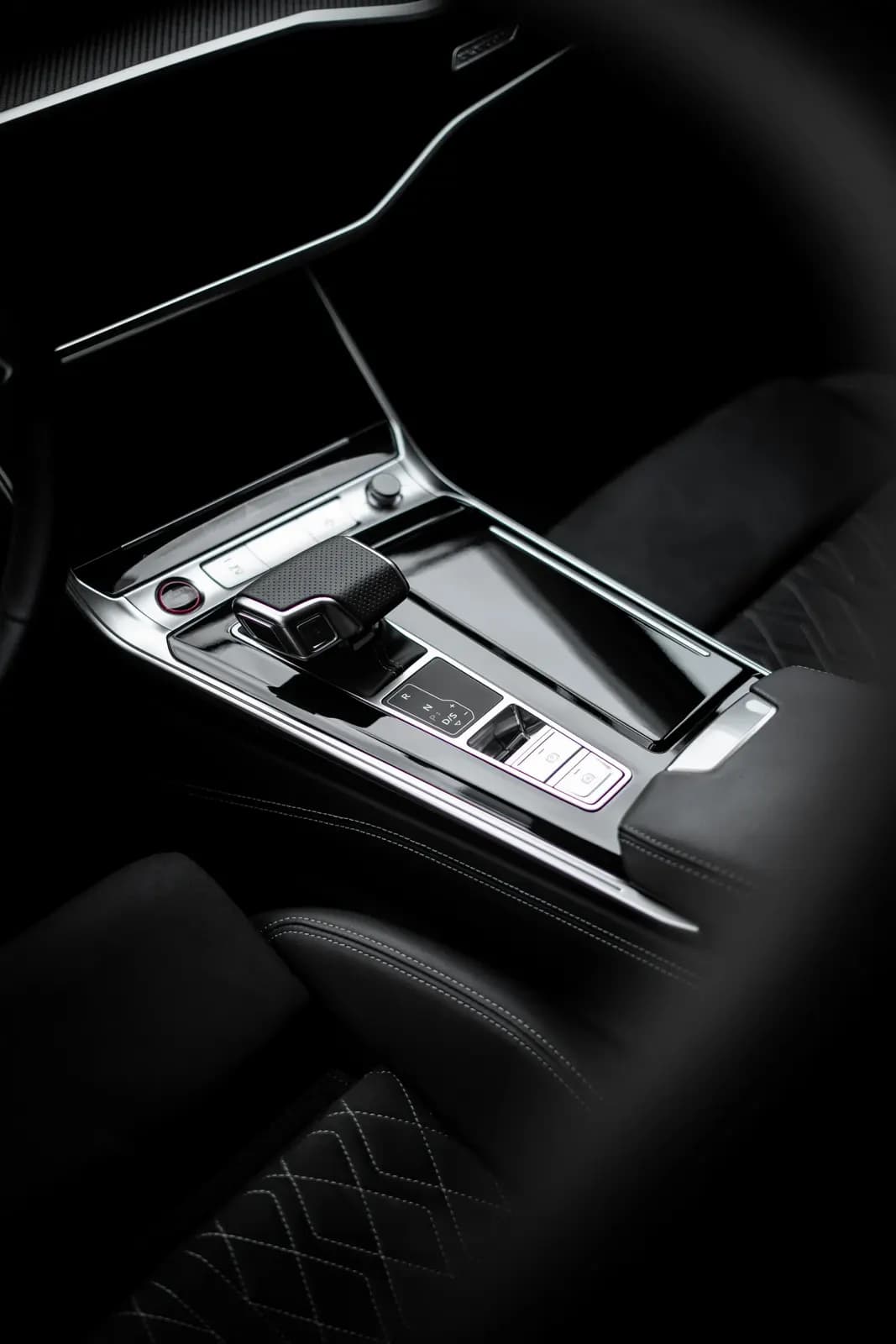Středový panel Audi s řadicí pákou a prošívaným sedadlem.