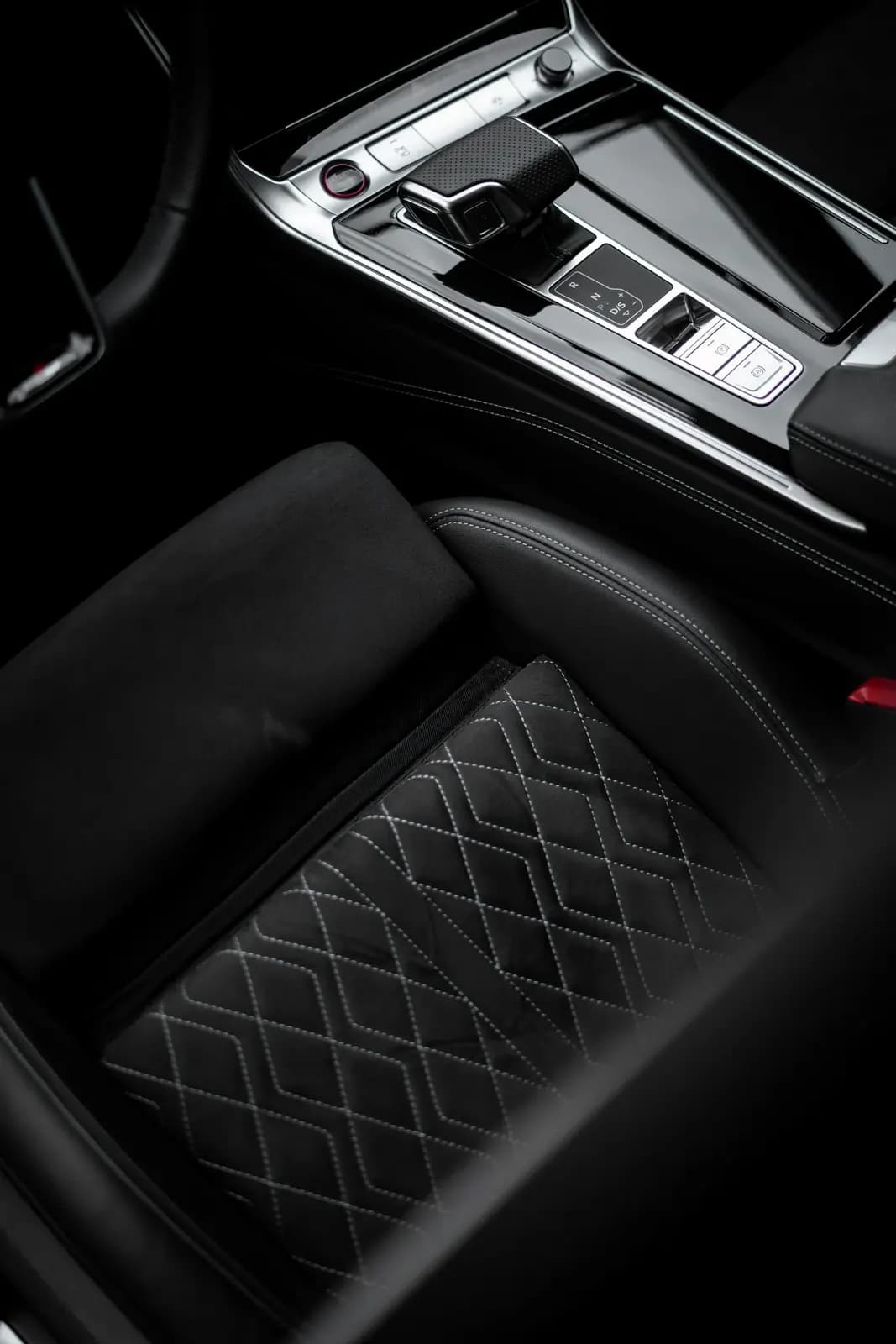 Detail prošívaného sedadla a středového panelu v interiéru Audi.