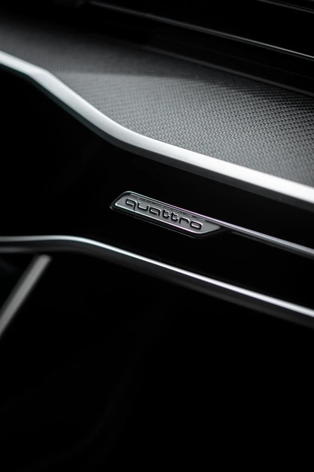 Detail odznaku quattro na palubní desce vozu Audi.