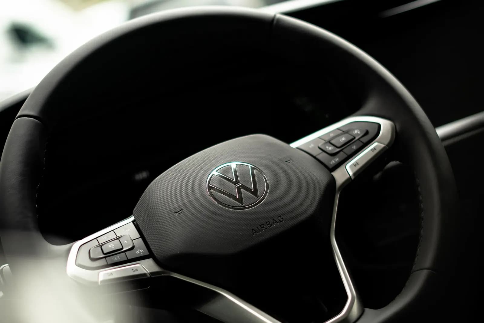 Close-up of a Volkswagen steering wheel with the VW logo and control buttons.