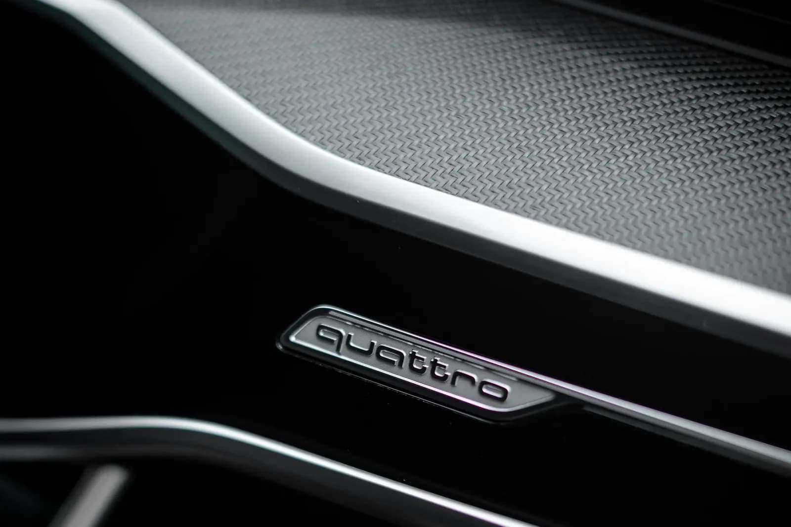 Close-up of the quattro badge on the carbon-textured dashboard of an Audi.