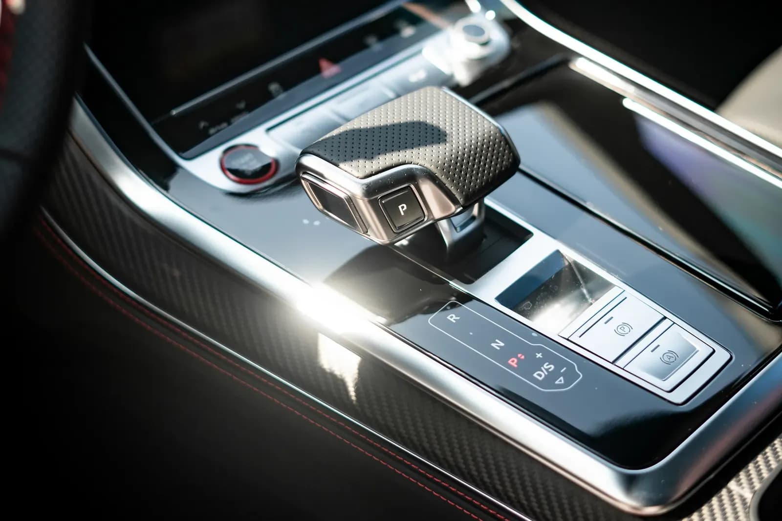 Close-up of the gear selector with the P button and the carbon trim of an Audi centre console.