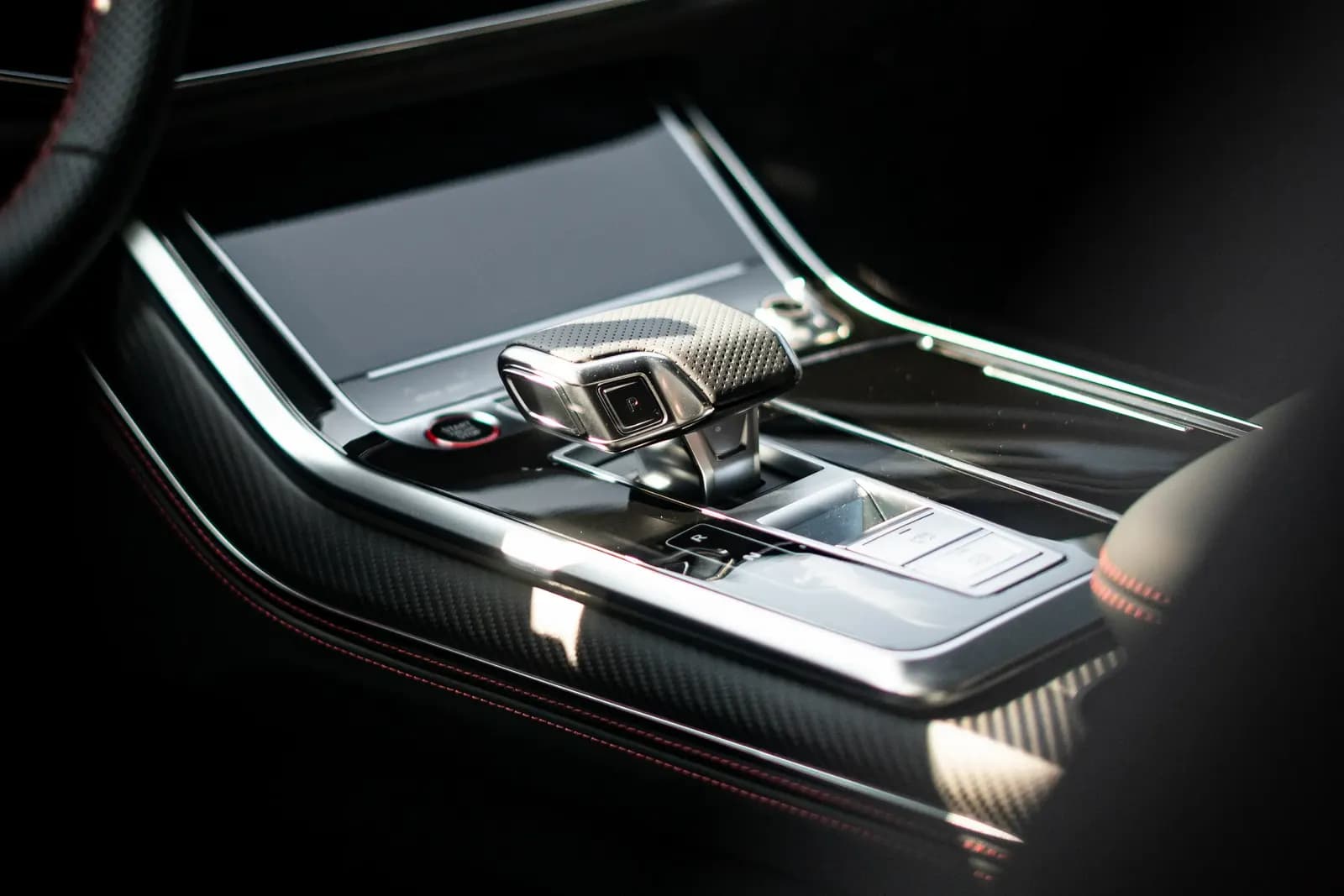 Gear selector and glossy centre console with carbon trim in an Audi interior.