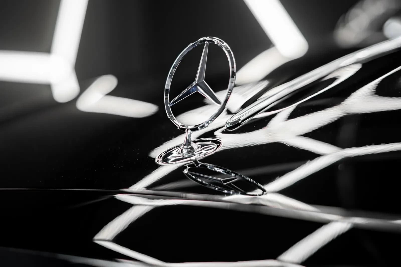 Close-up of the chrome Mercedes-Benz bonnet ornament on a glossy black bodywork.