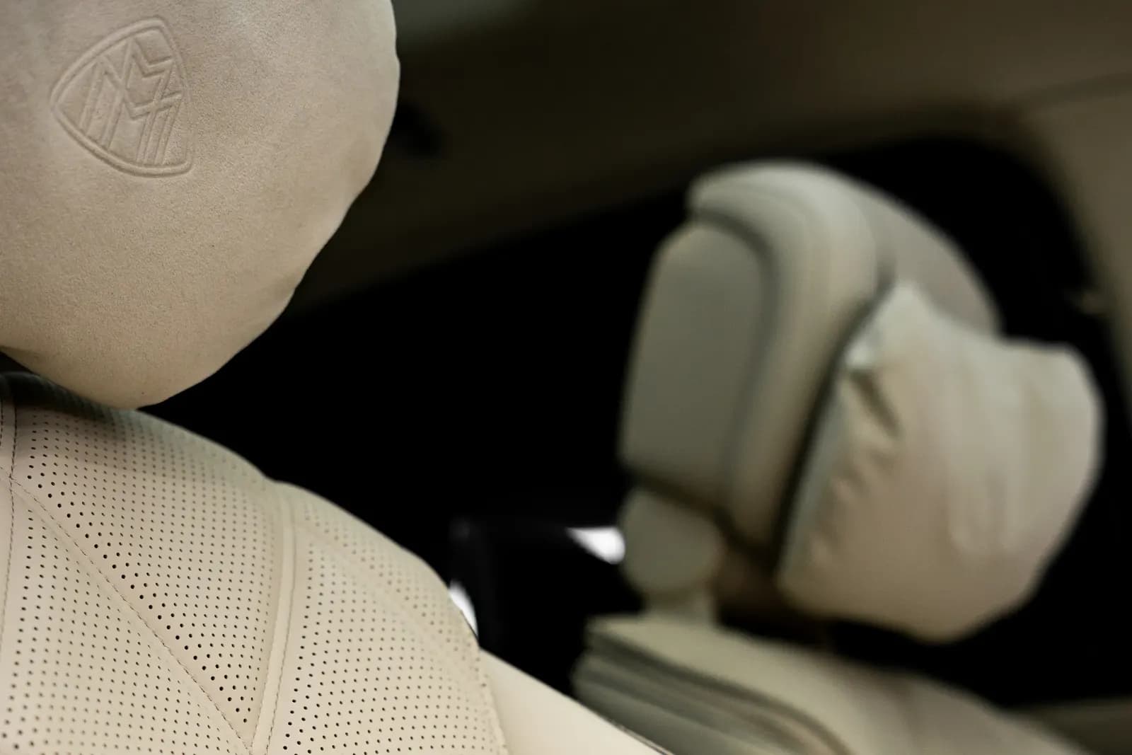 Close-up of a headrest with the Maybach logo on the front seat of the car.