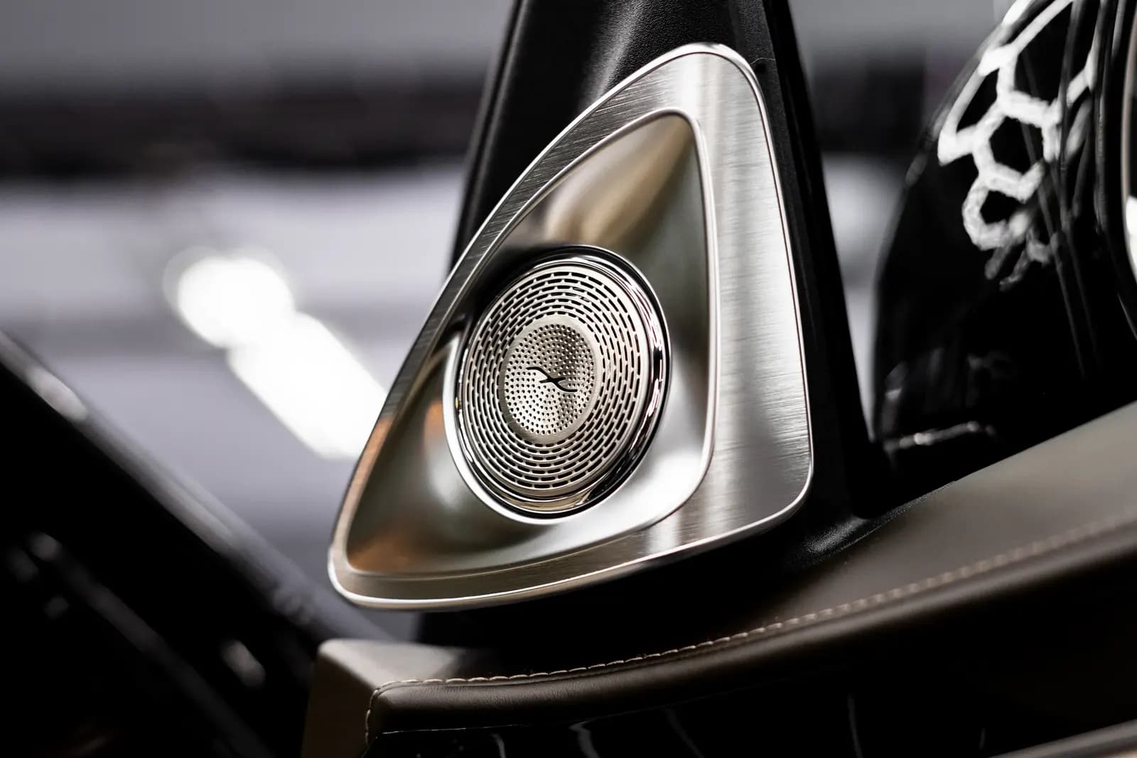 Close-up of a triangular speaker grille in a luxury car's door panel.