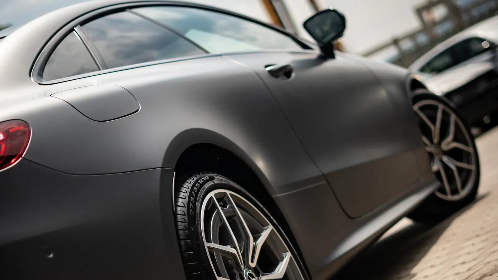 Rear side view of a matte grey Mercedes-AMG coupe parked outdoors.