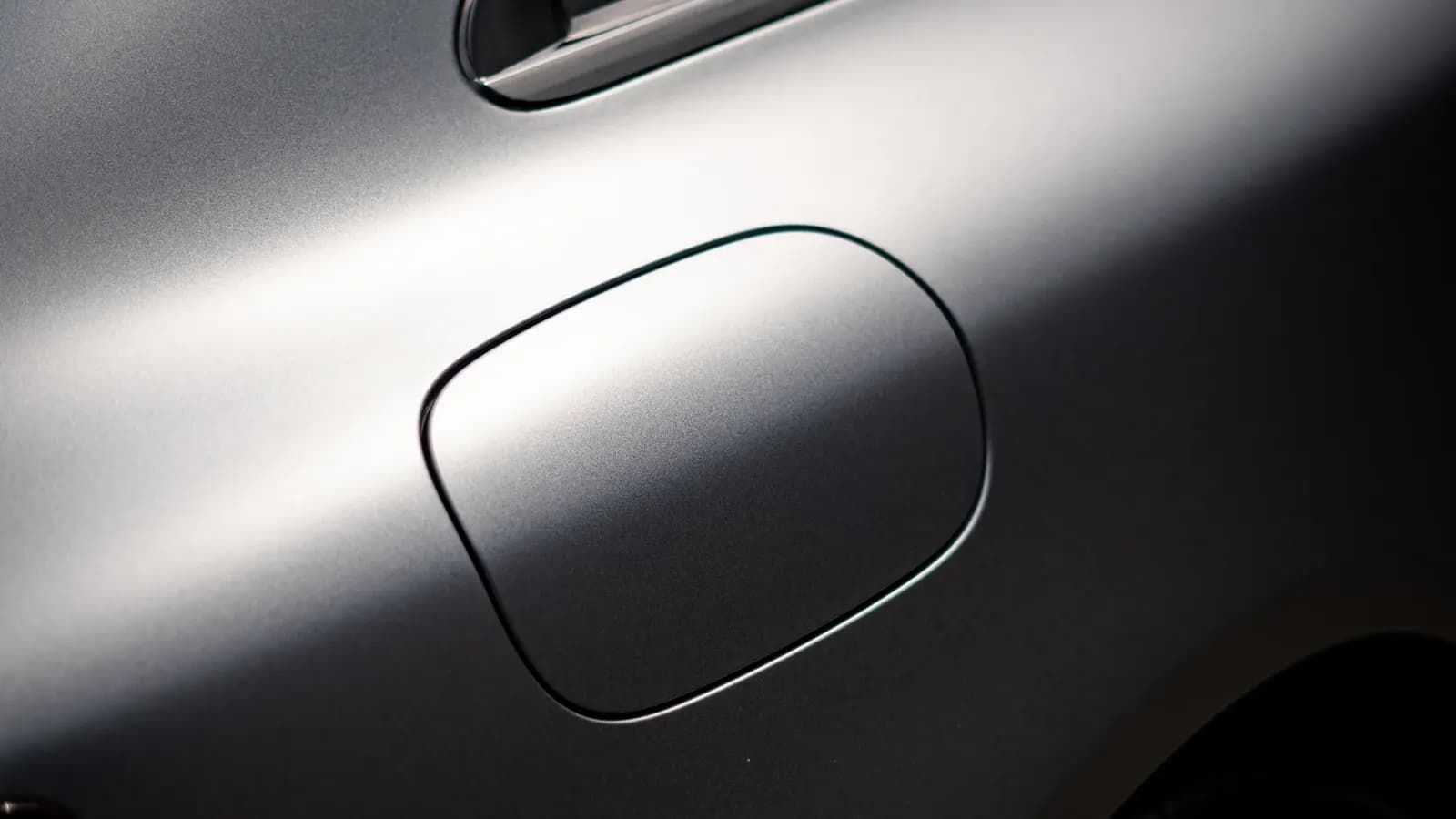 Close-up of a fuel filler flap on a silver car's bodywork.
