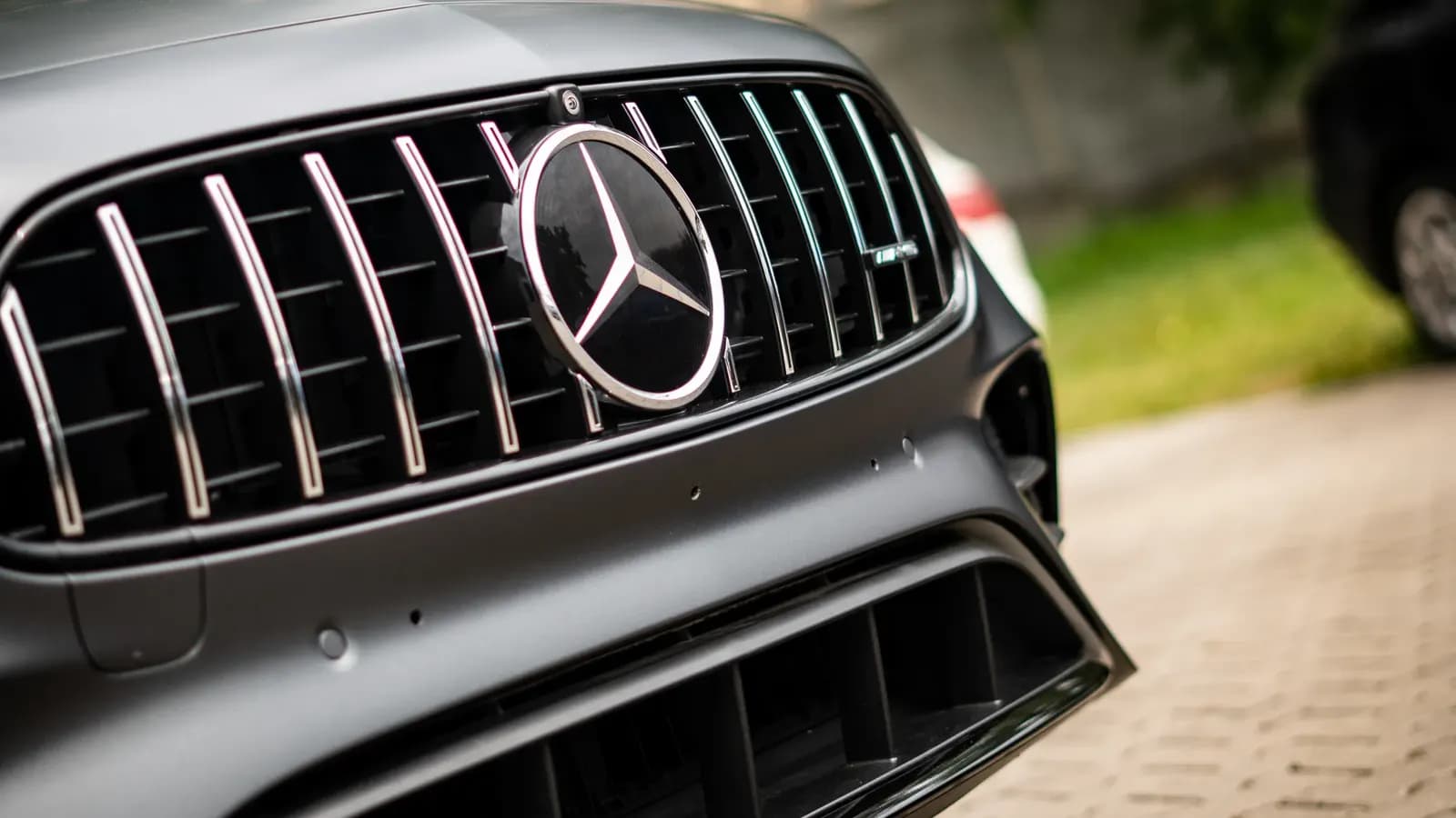 Close-up of the front grille with the Mercedes-AMG logo on a matte grey car.