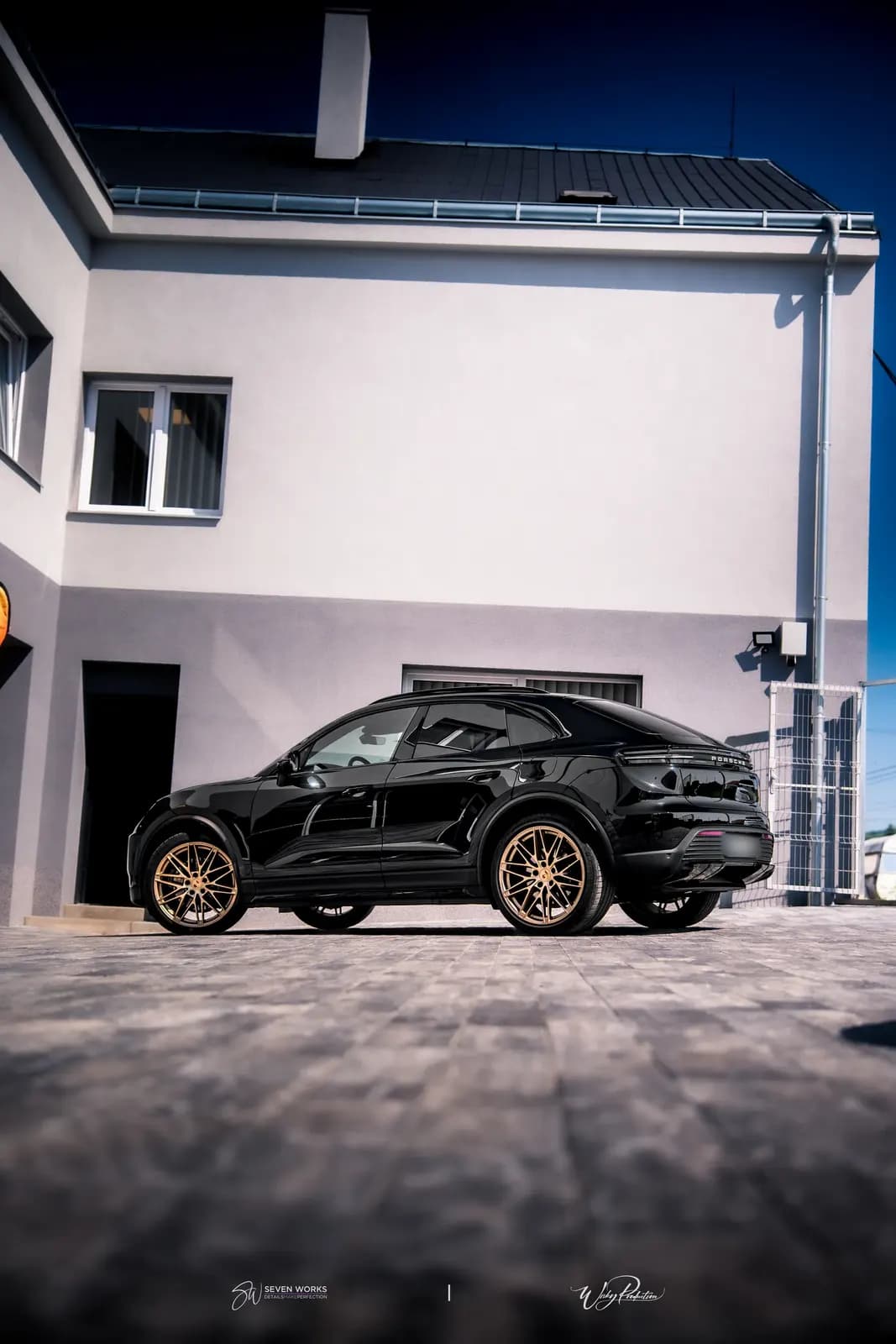 Low-angle side view of a black SUV coupe against a dark blue sky and a house.