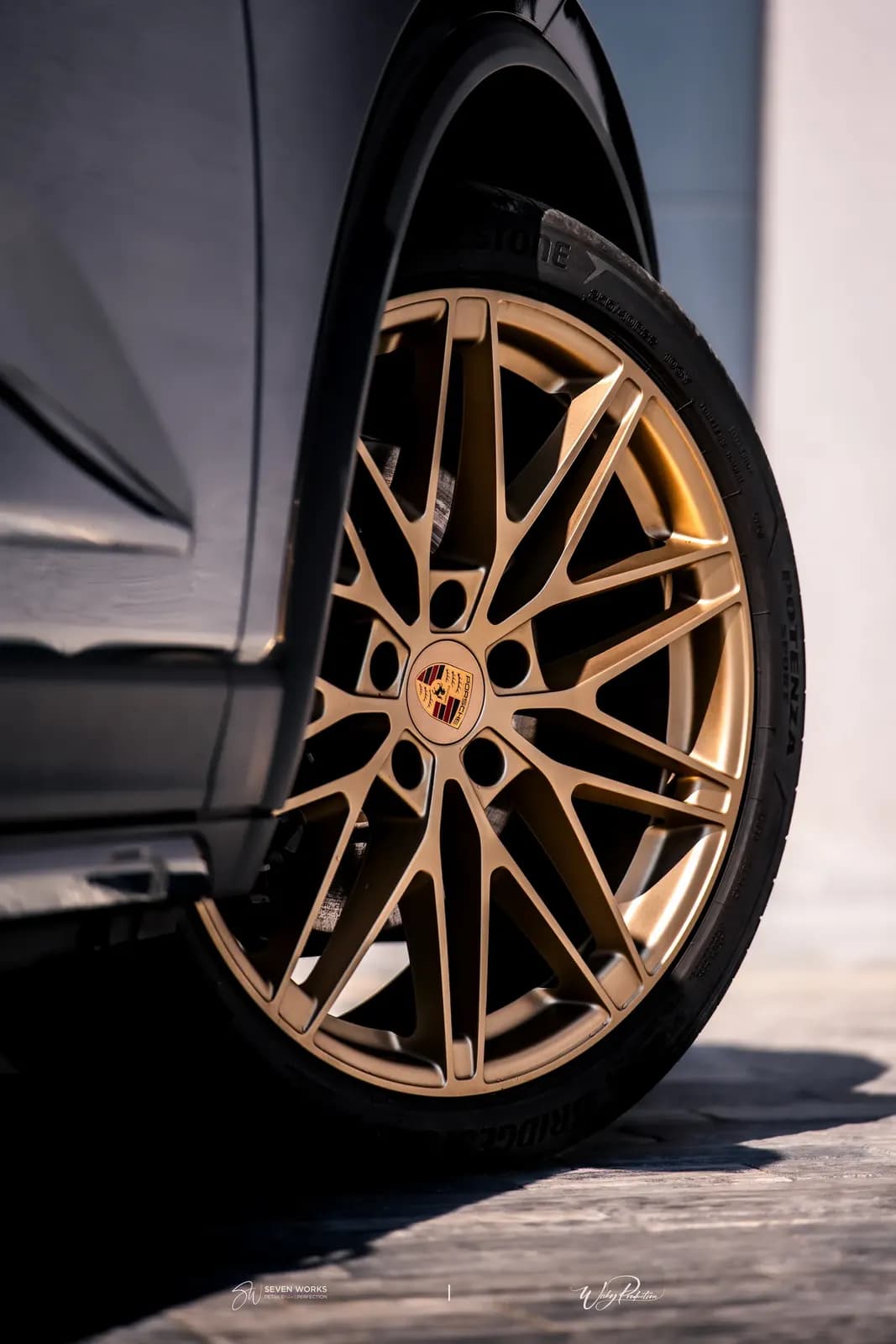 Close-up of a bronze wheel with the Porsche crest on a black car.