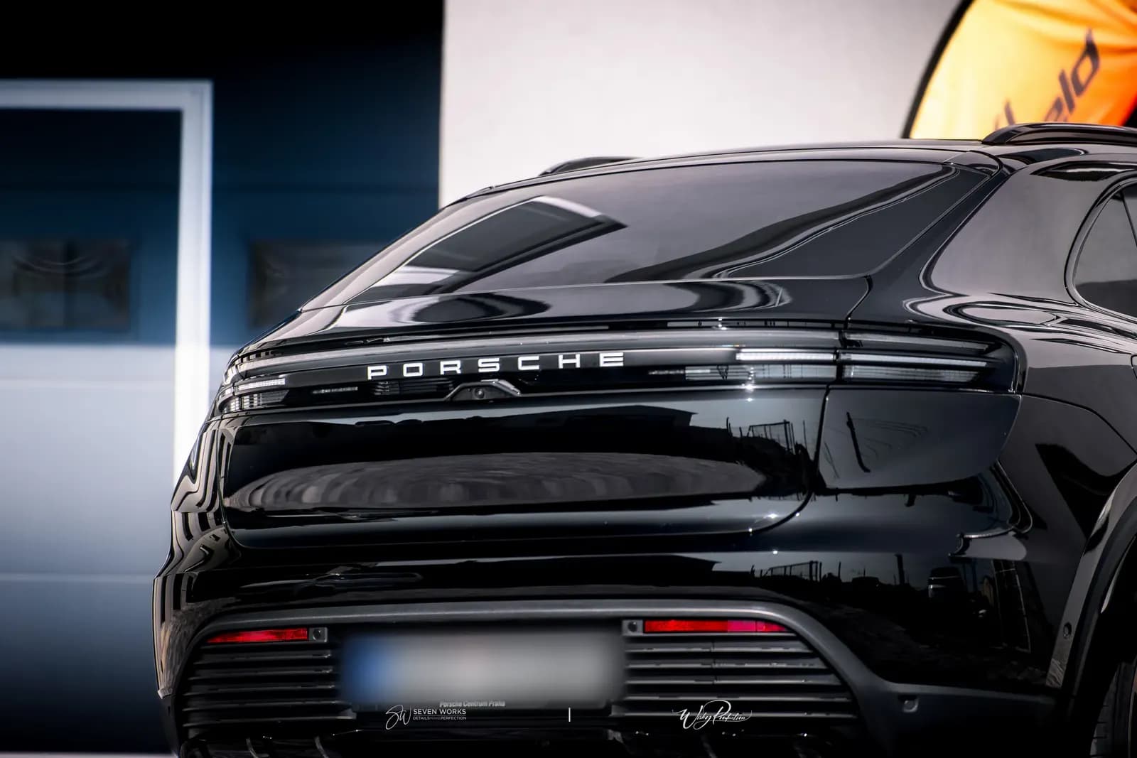 Rear view of a black Porsche SUV in the courtyard, showing the tail lights and Porsche lettering.