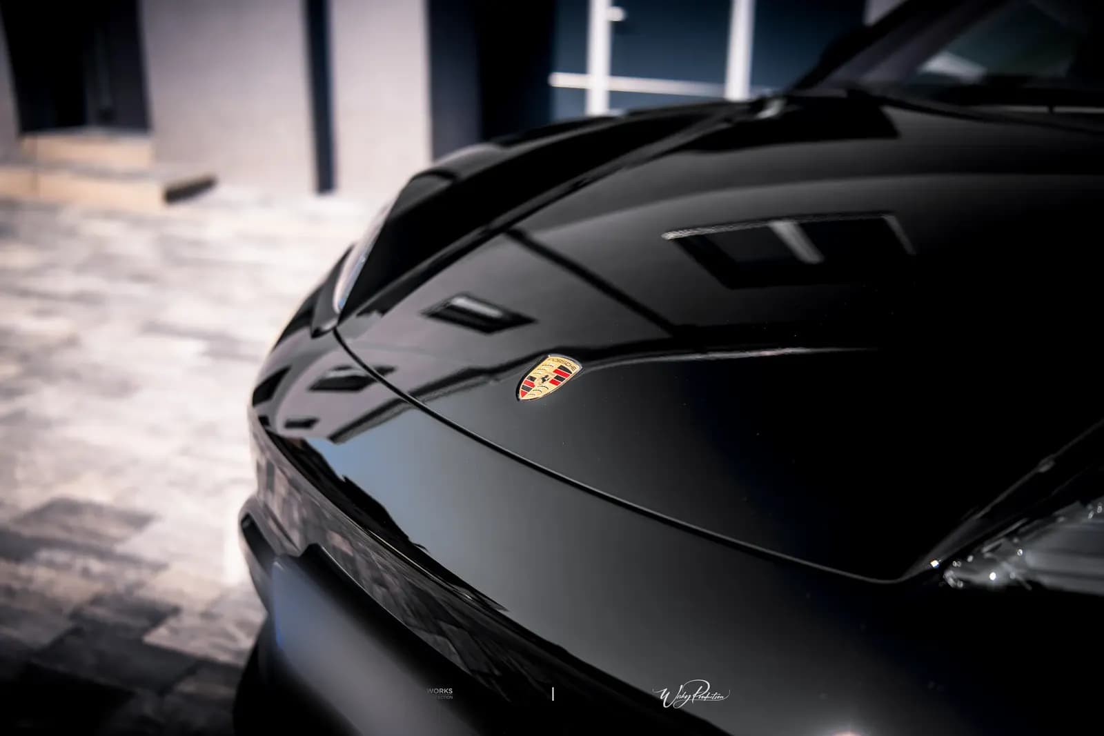 Close-up of the bonnet and Porsche badge on a black car.