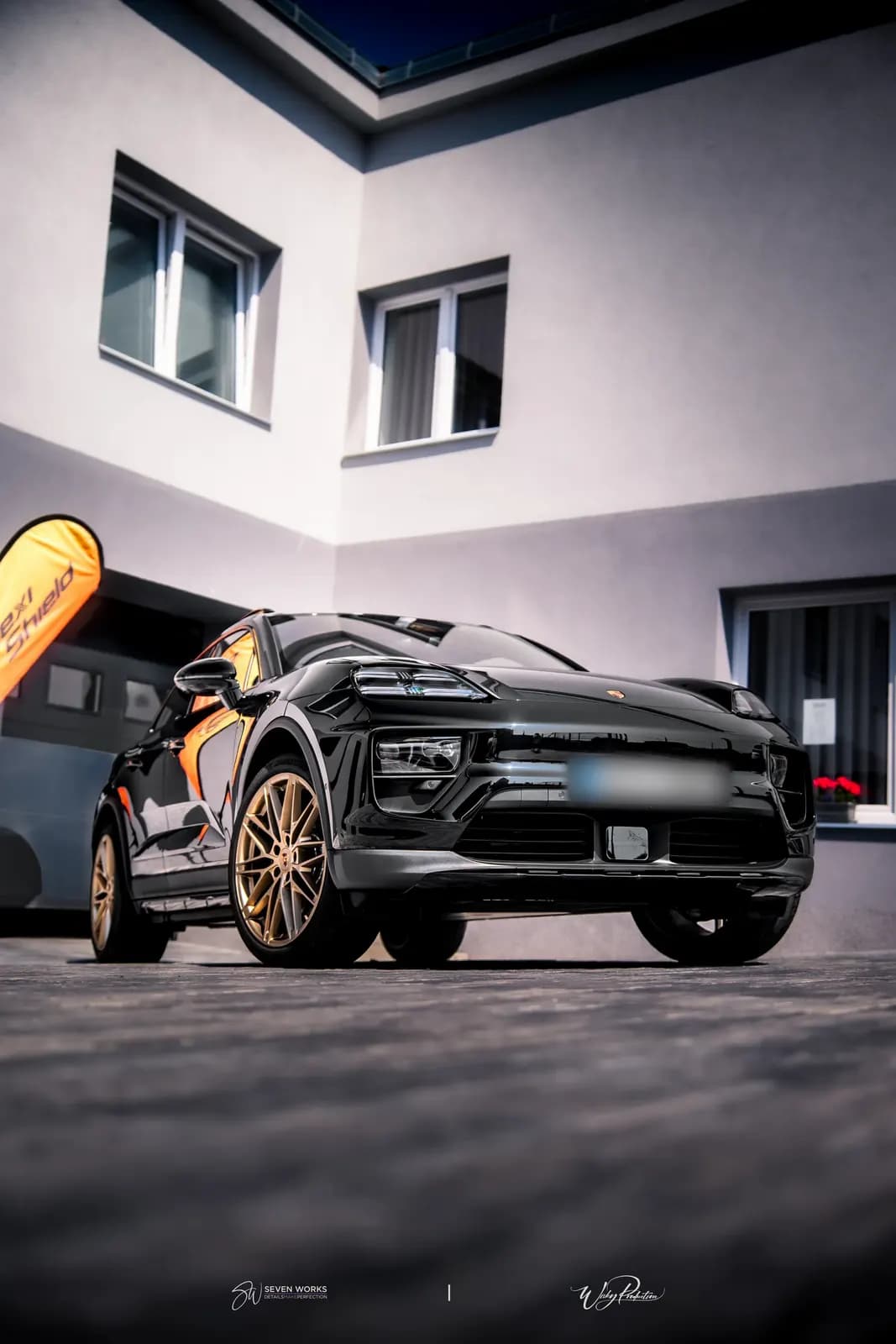 Low-angle front view of a black Porsche SUV outside the workshop.