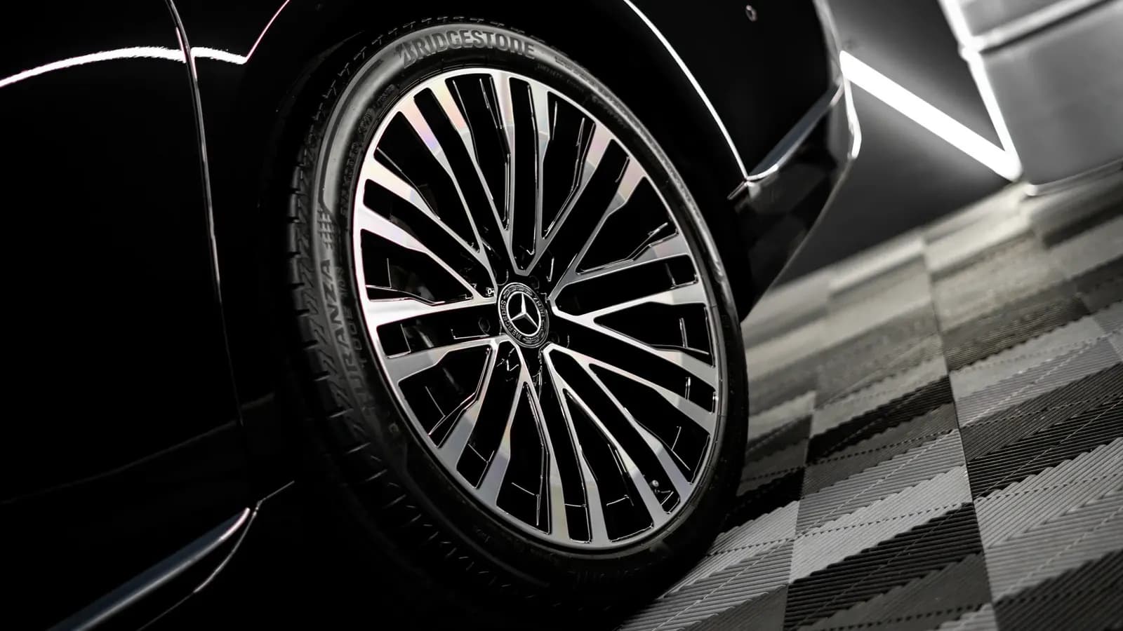 Close-up of a glossy wheel with a Mercedes-Benz logo on a black car.