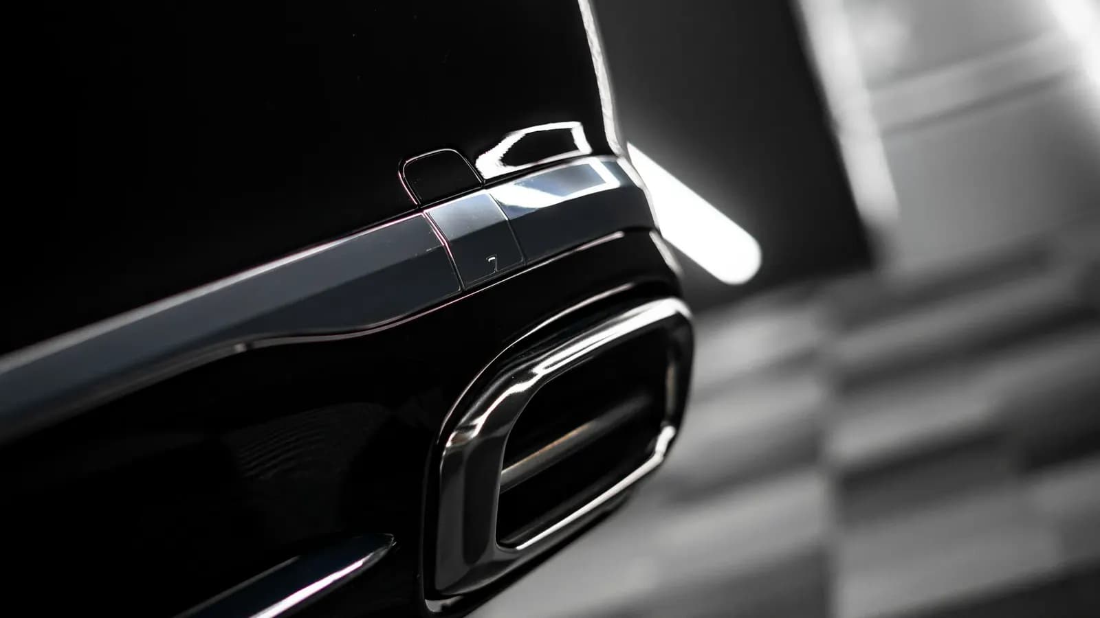 Close-up of a chrome exhaust tip on a black car.