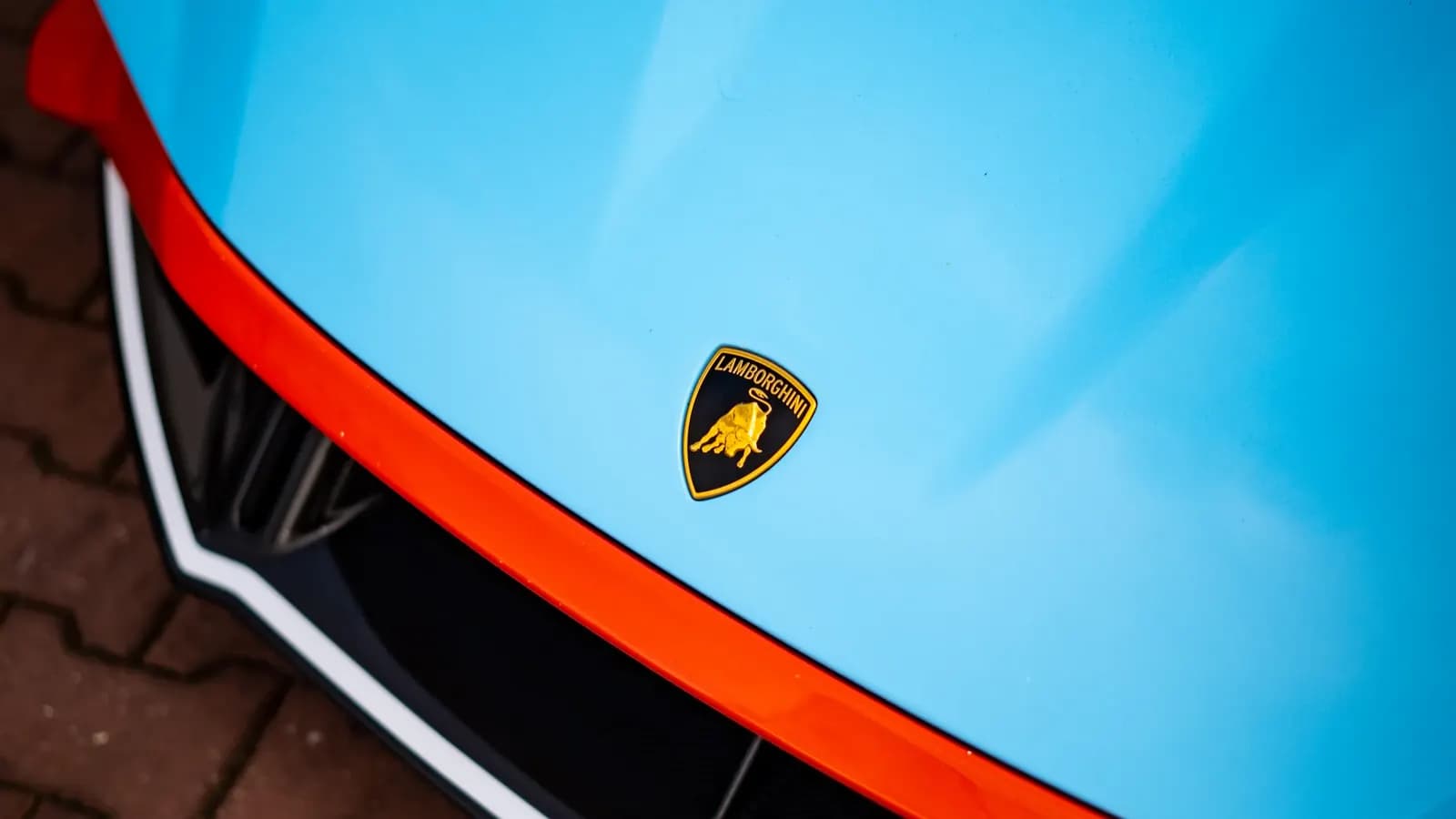 Close-up of the yellow Lamborghini emblem on the bonnet of a light blue car.