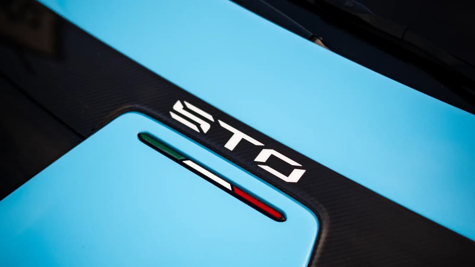Close-up of the STO lettering and Italian flag on a carbon-fibre panel of a Lamborghini.