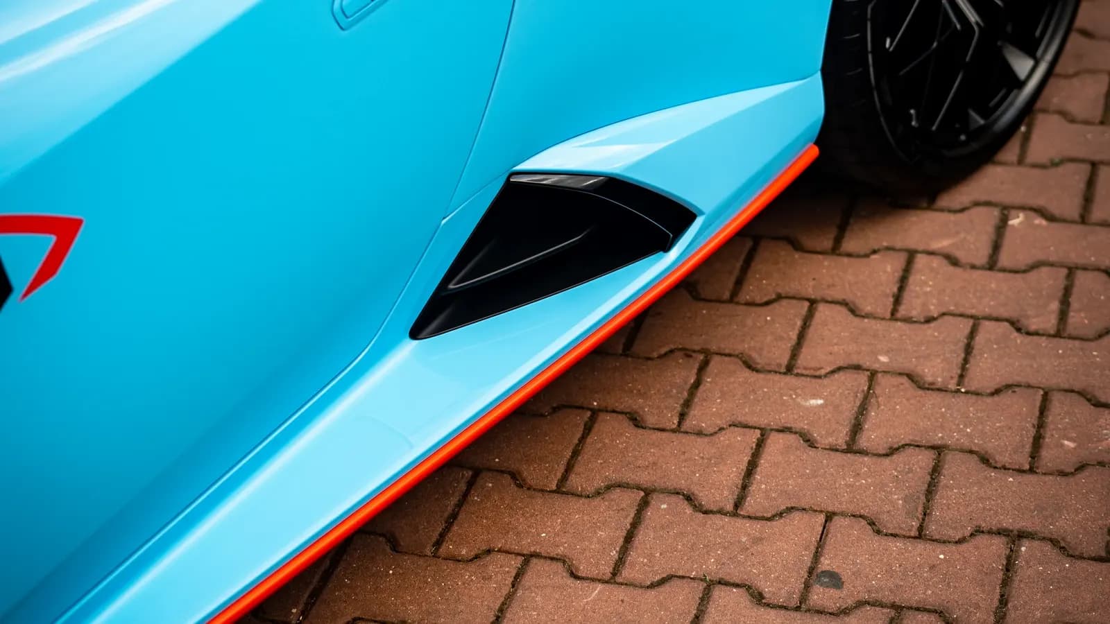 Close-up of the side sill and air intake on a light blue Lamborghini.
