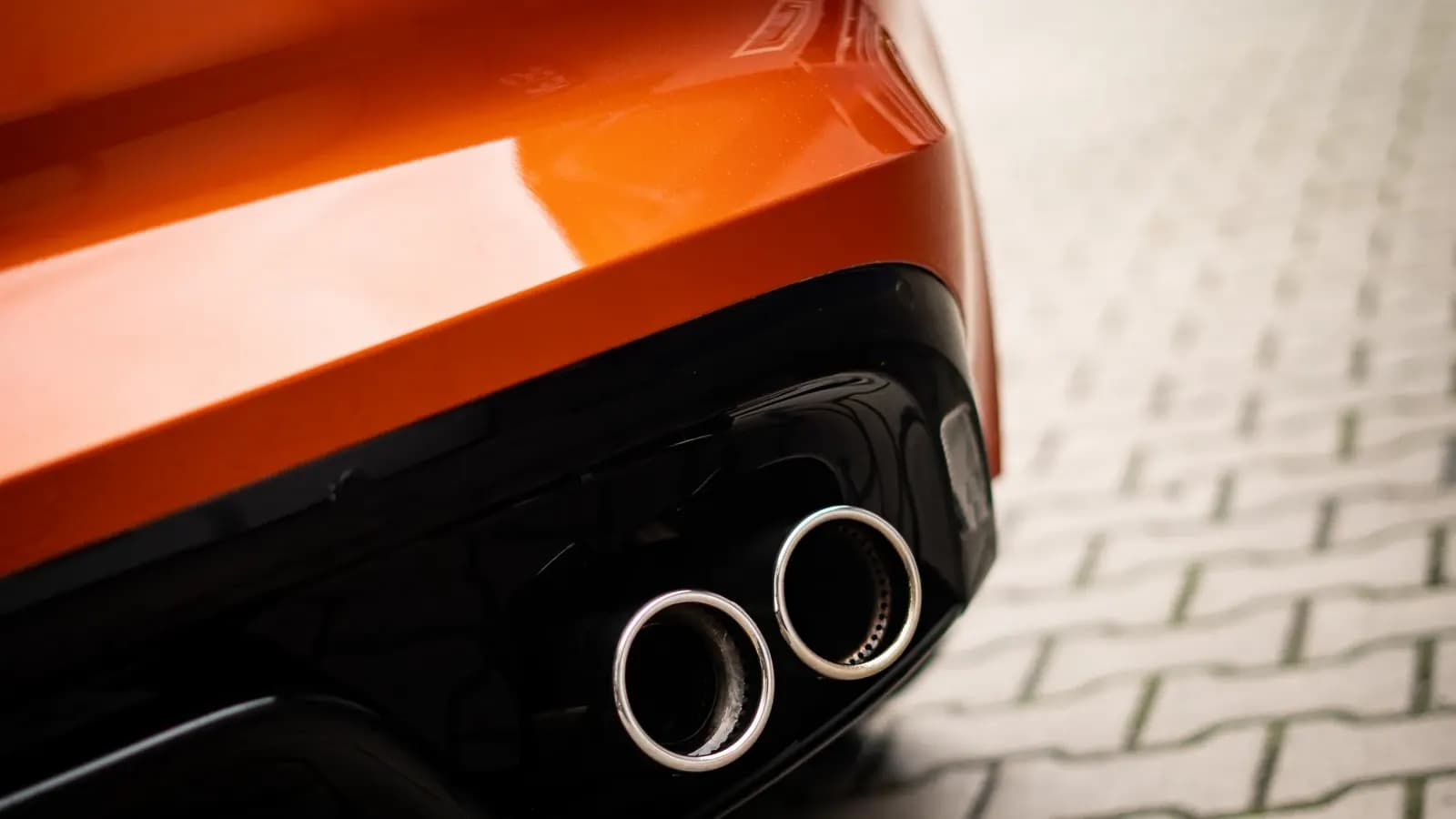 Close-up of the twin exhaust tips on an orange car.