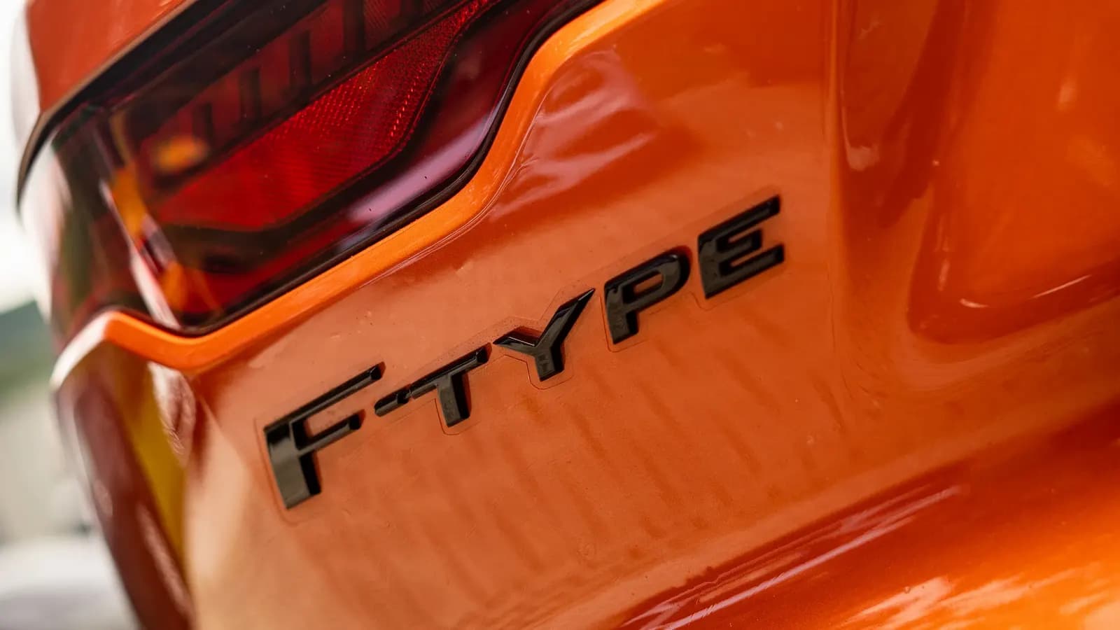 Close-up of the F-TYPE lettering and tail light on an orange car.