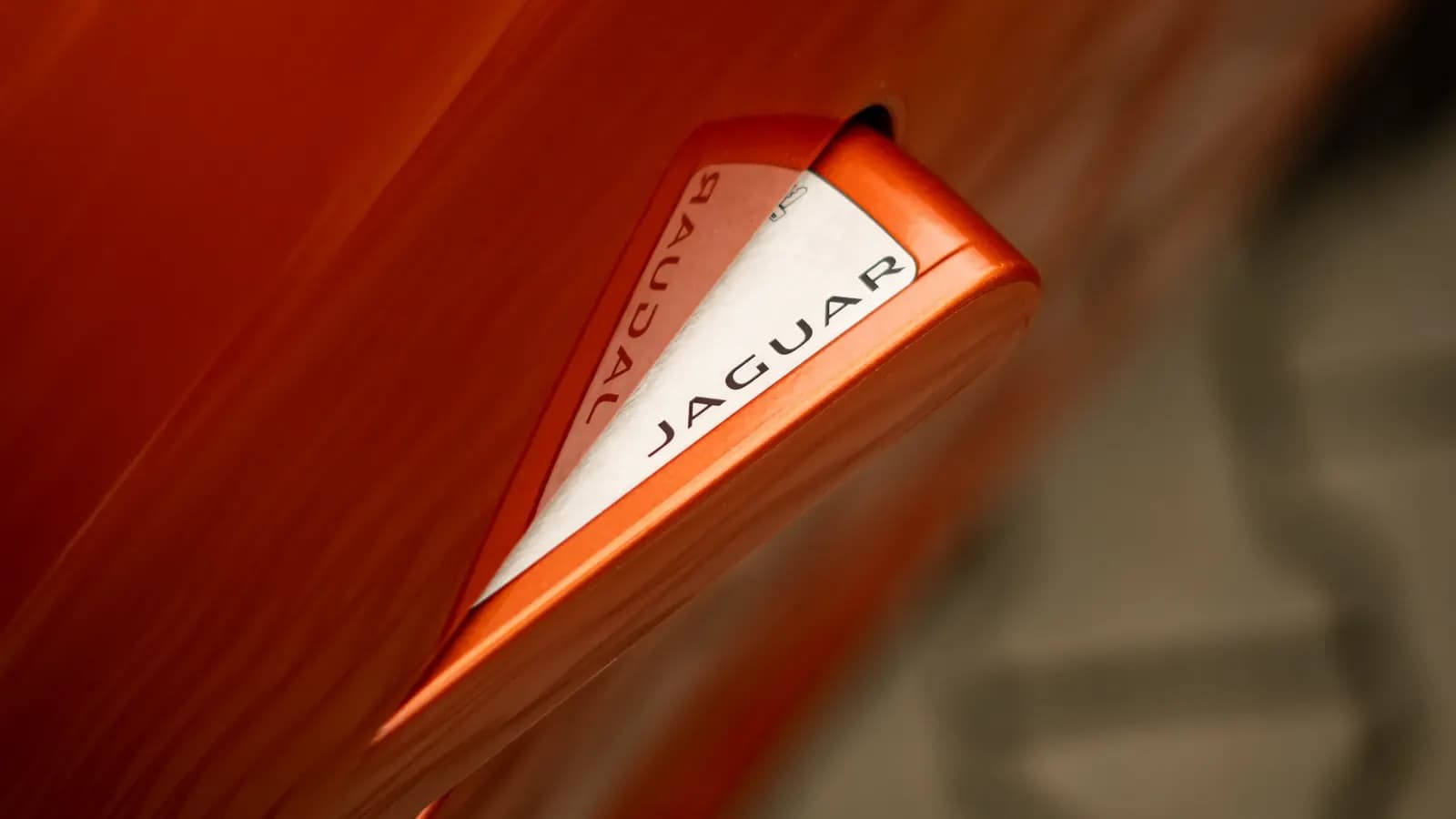 Close-up of the deployed door handle with Jaguar lettering on an orange car.