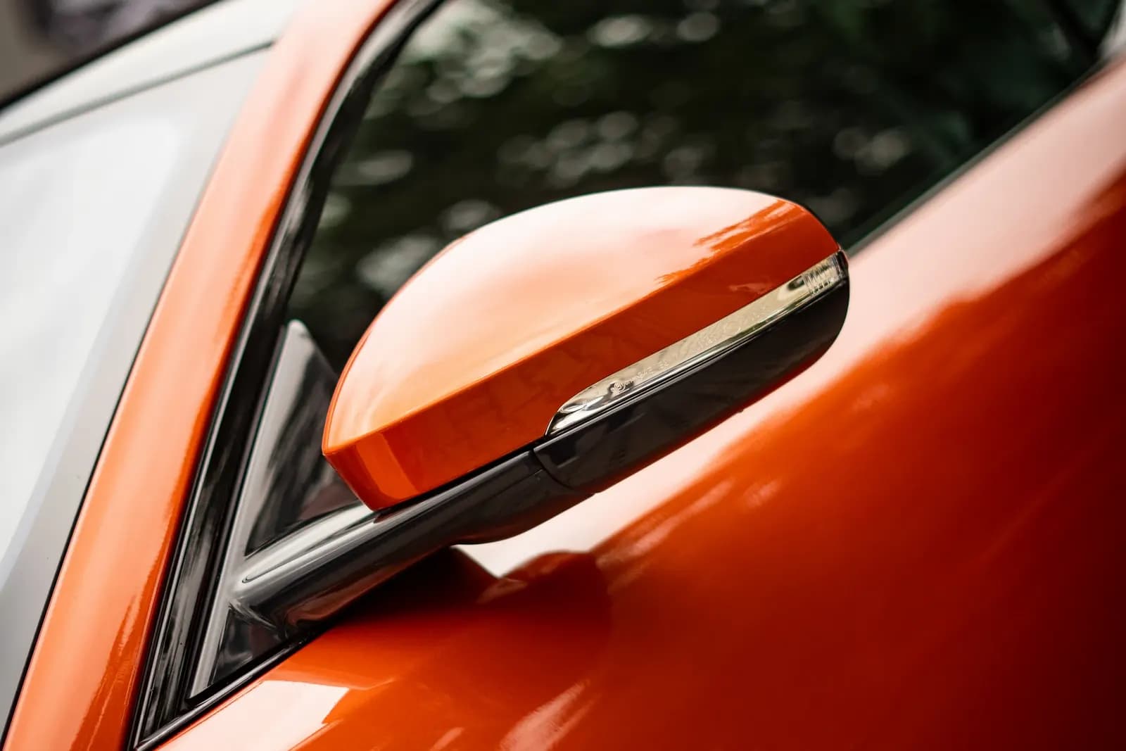Close-up of the side mirror on an orange car.