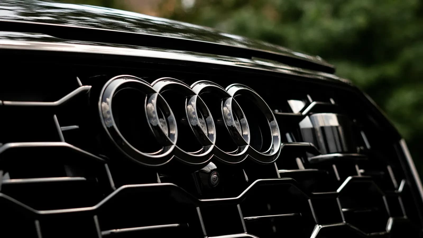 Macro shot of the Audi badge on a dark car's front grille.