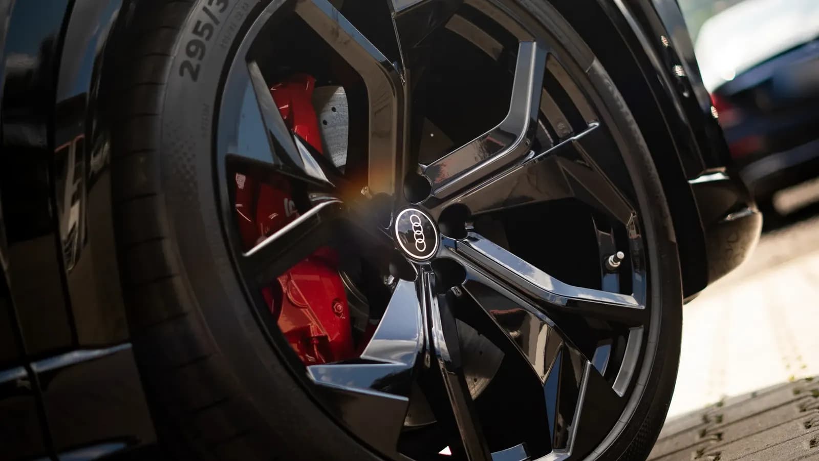 Close-up of a black alloy wheel with a red brake caliper and Audi badge.