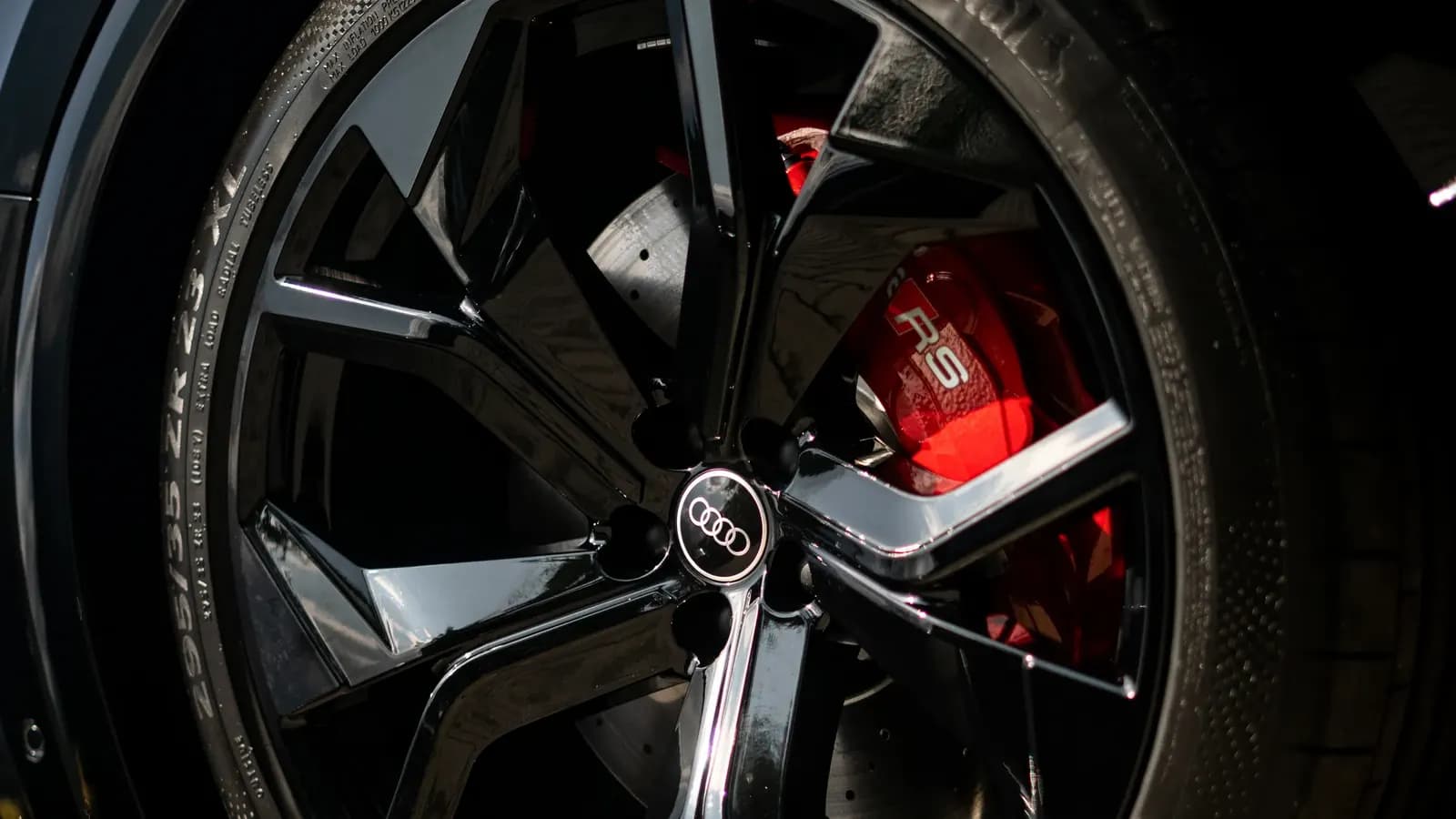 Macro shot of a black alloy wheel and red brake caliper marked RS.
