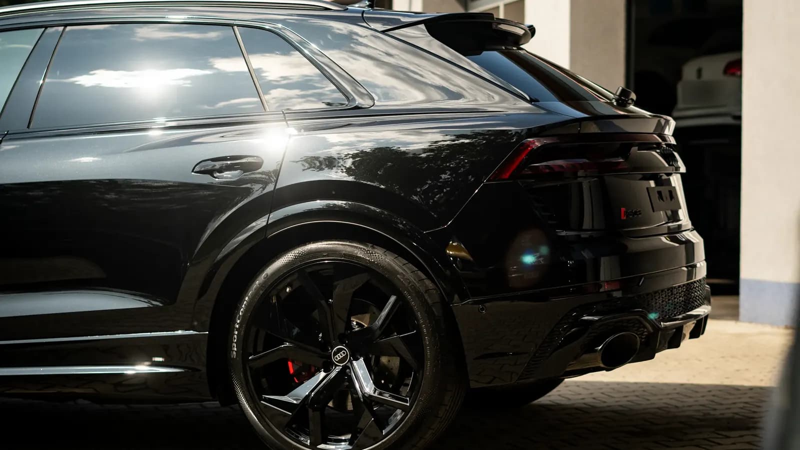 Side and rear view of a black sports SUV parked in front of a house.