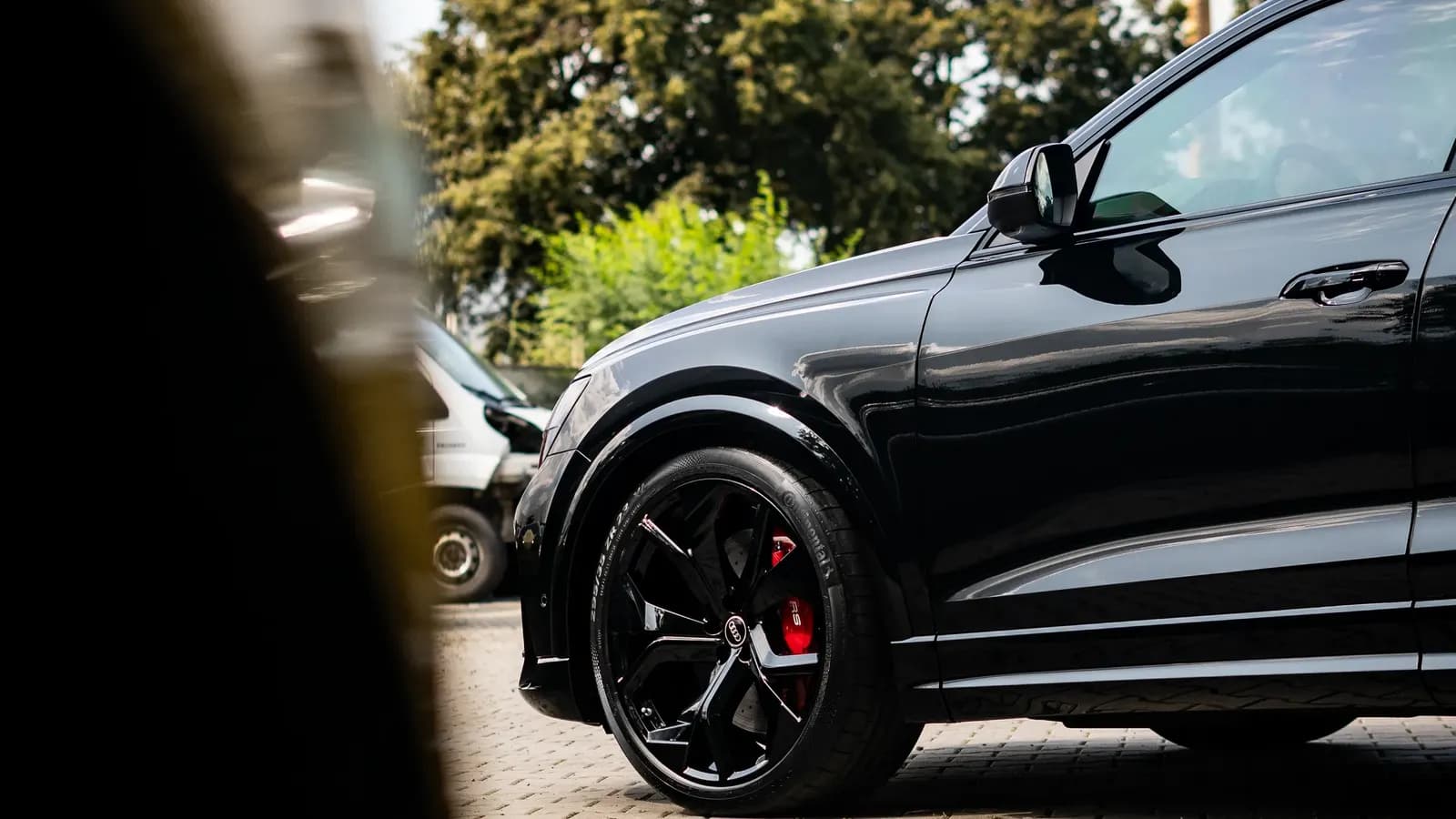 Side view of a black sports SUV, partly framed by a blurred silhouette in the foreground.
