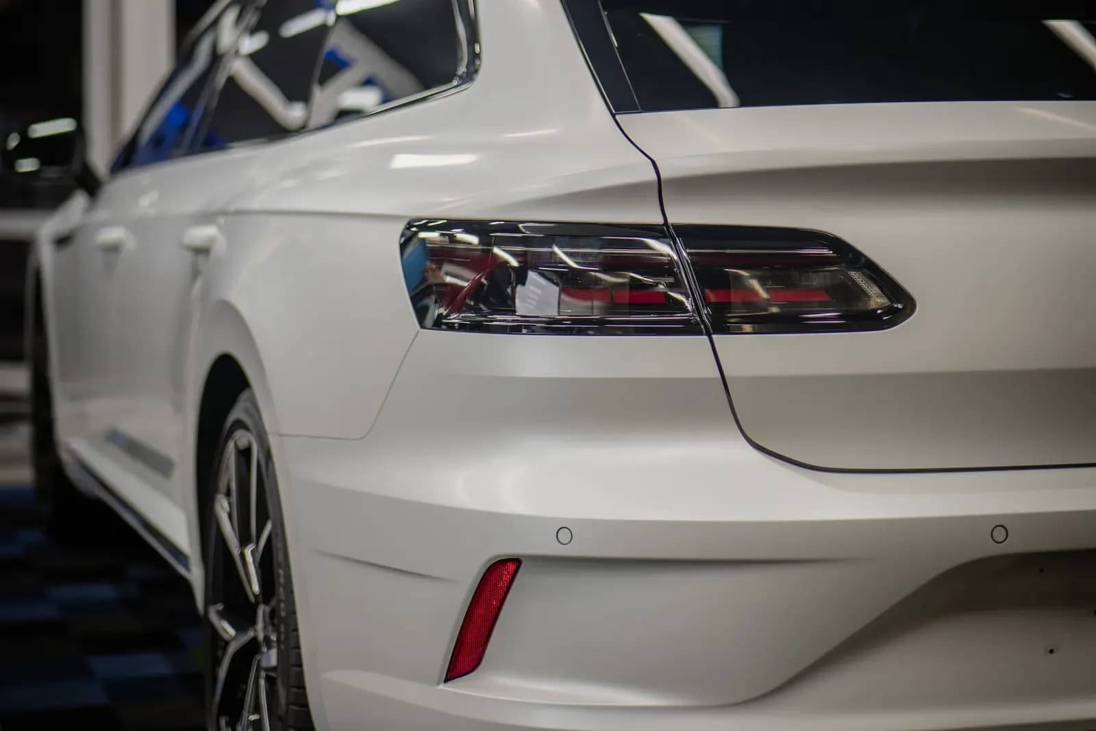 Detail zadního světla bílého vozu v interiéru showroomu.