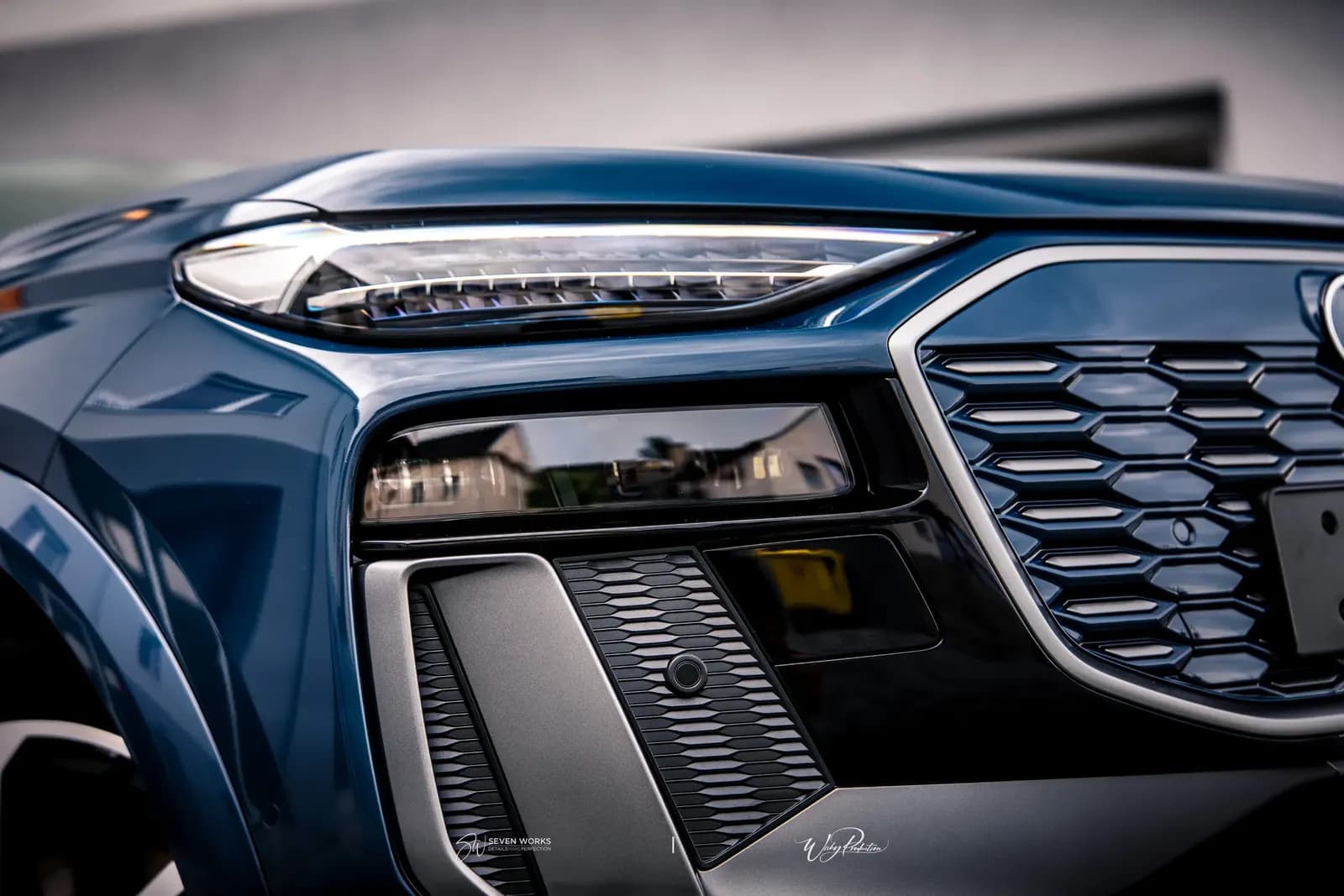 Makro detail světla a masky chladiče tmavě modrého Audi SUV.