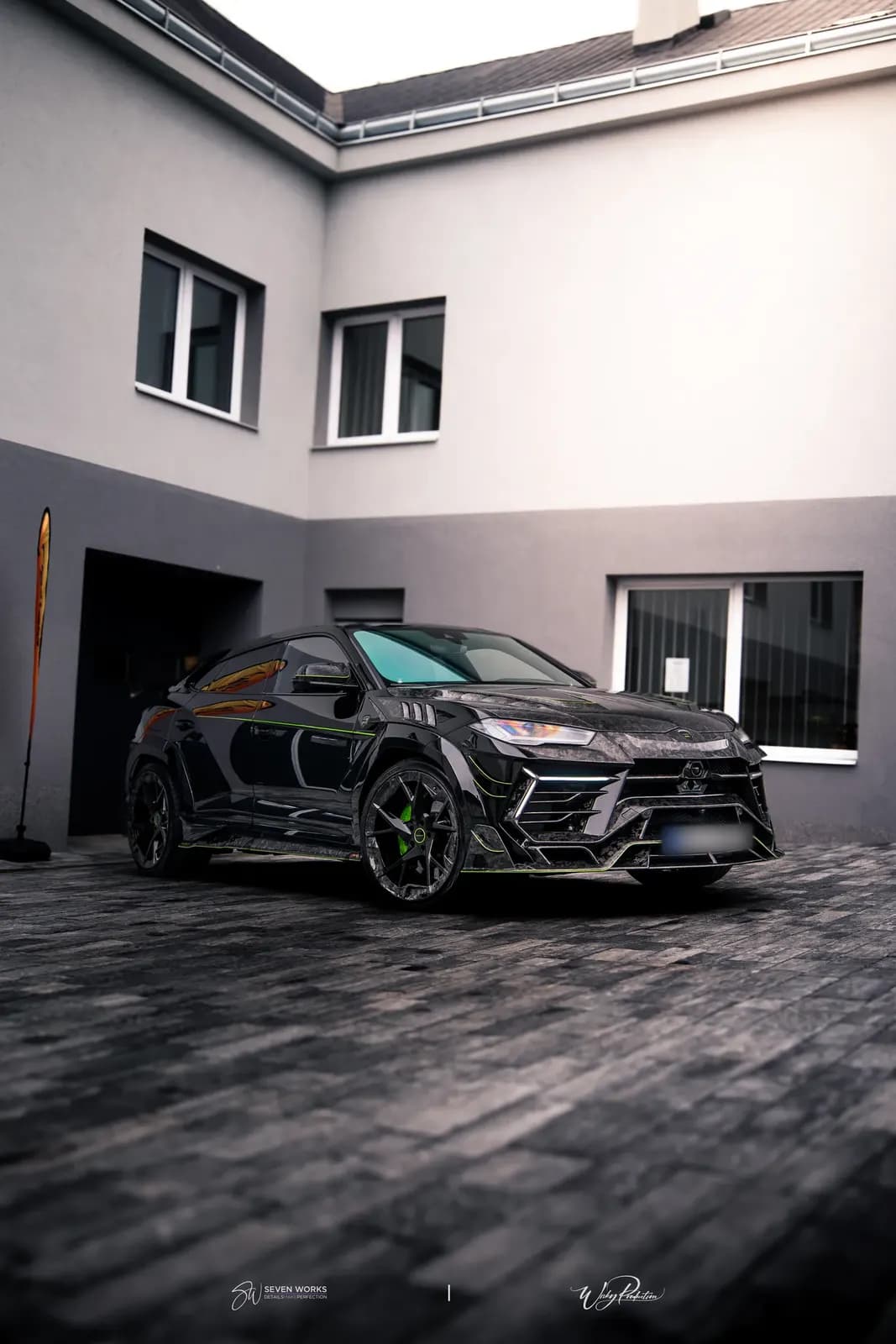 Lamborghini Urus s karbonovým widebody kitem před šedou budovou, široký čelně-boční záběr s prostorem pro text.