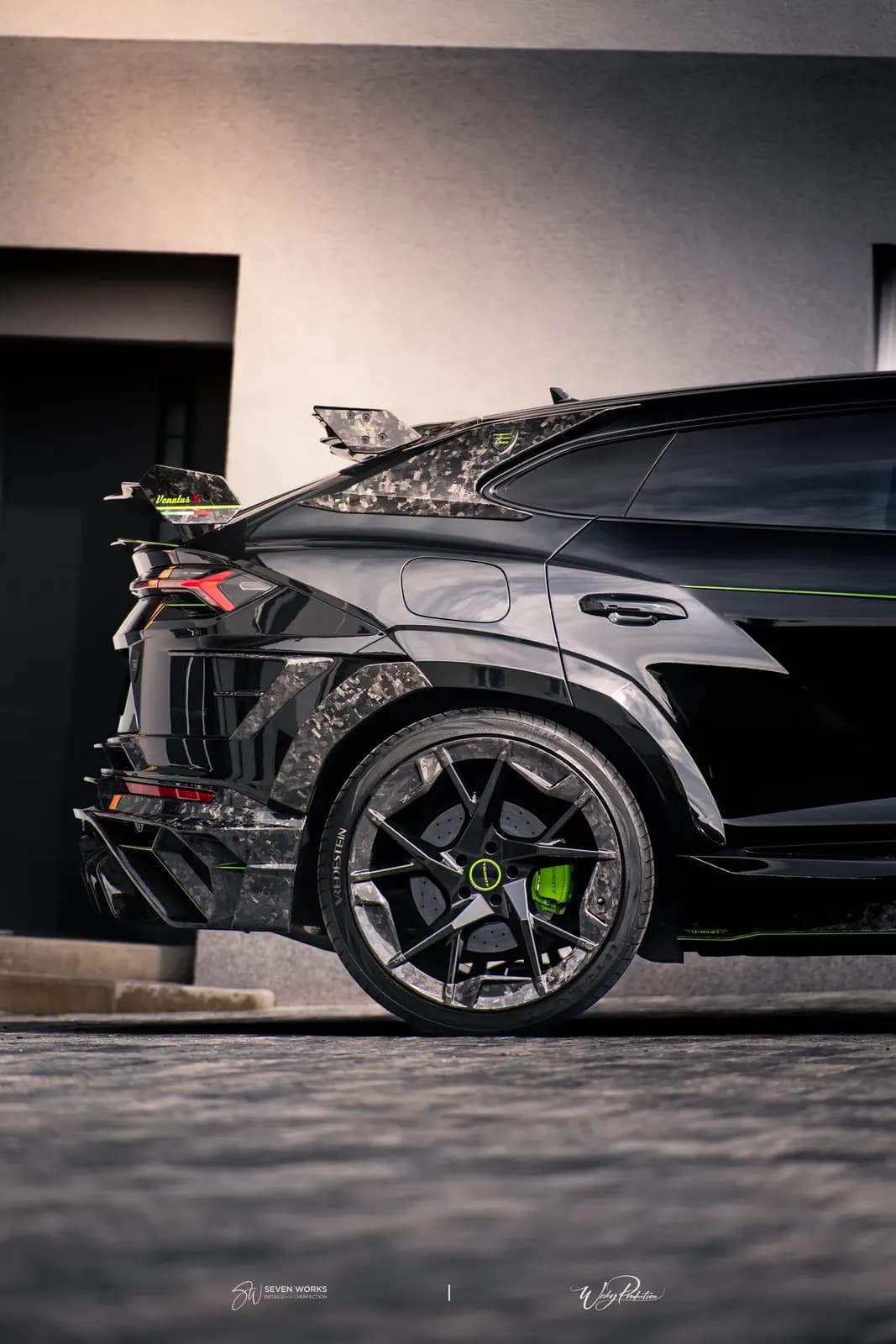 Zadní boční pohled na Lamborghini Urus se spoilerem a karbonovými prvky před domem.