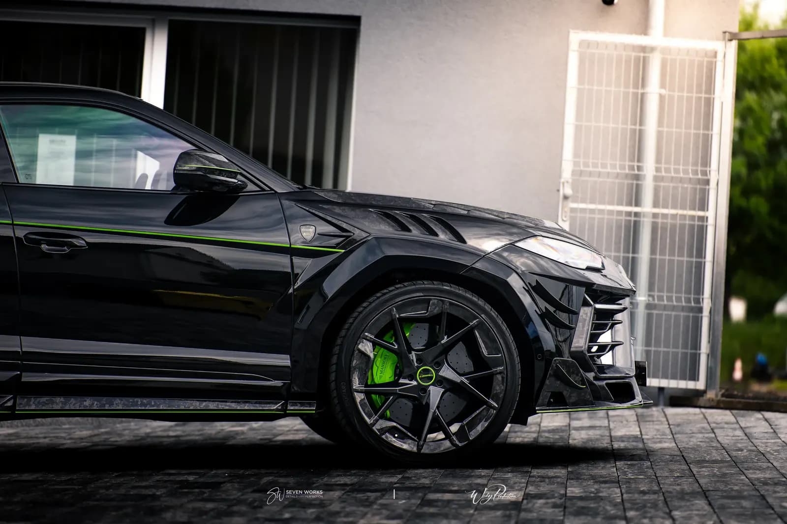 Detail předního kola a boční části karbonového widebody kitu Lamborghini Urus u domu.