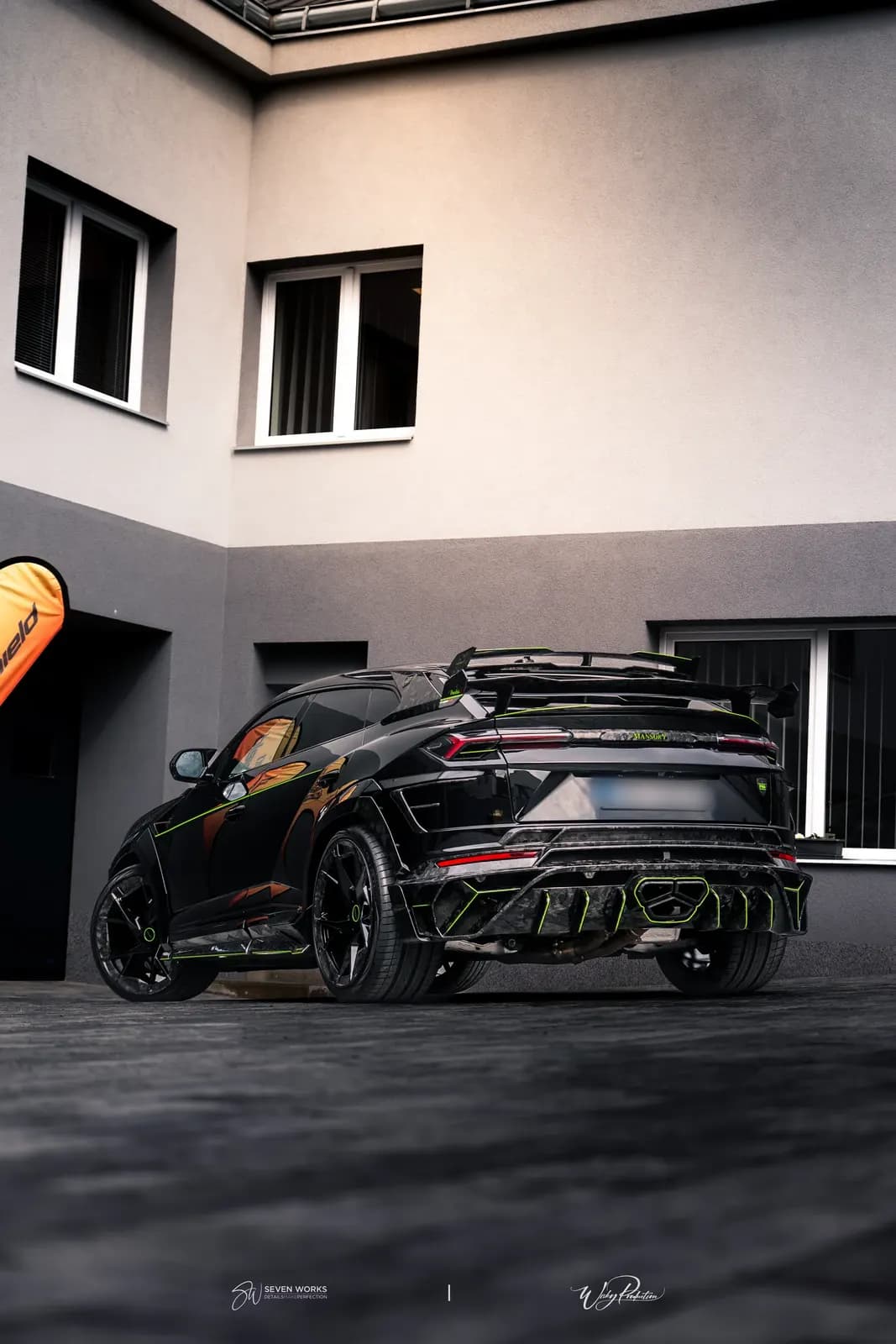 Lamborghini Urus zezadu-boku před vícepodlažní budovou v podvečerním světle.
