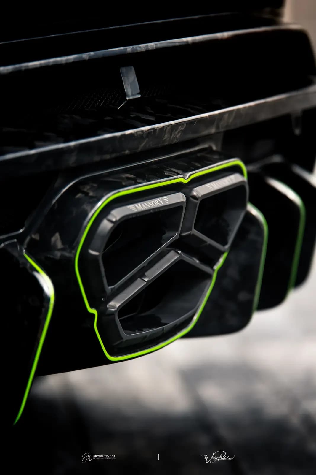 Makro detail výfukové koncovky s logem Mansory a zeleným lemováním na Lamborghini Urus.