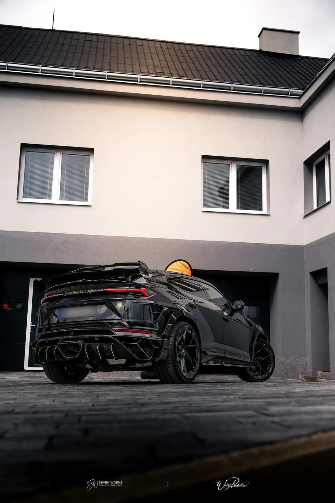 Lamborghini Urus zezadu-boku před domem s otevřenou střešní plochou oblohy vhodnou pro text.