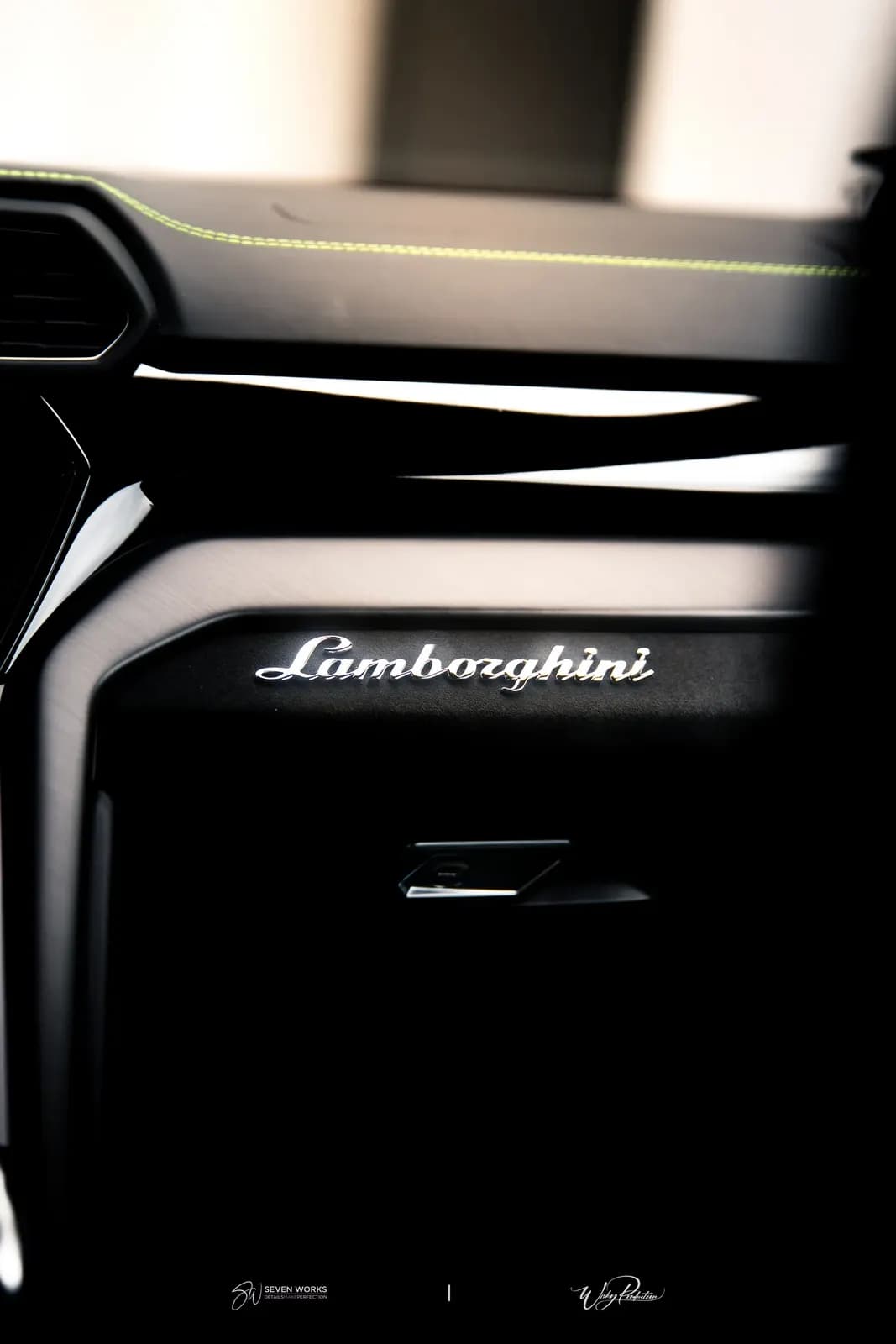 Detail palubní desky s emblémem Lamborghini a zeleným prošíváním.