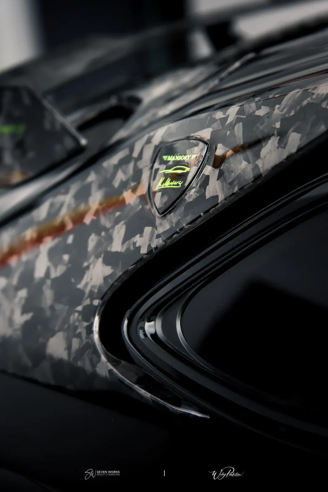 Makro detail odznaku Mansory na karbonovém sloupku karoserie vedle okna.