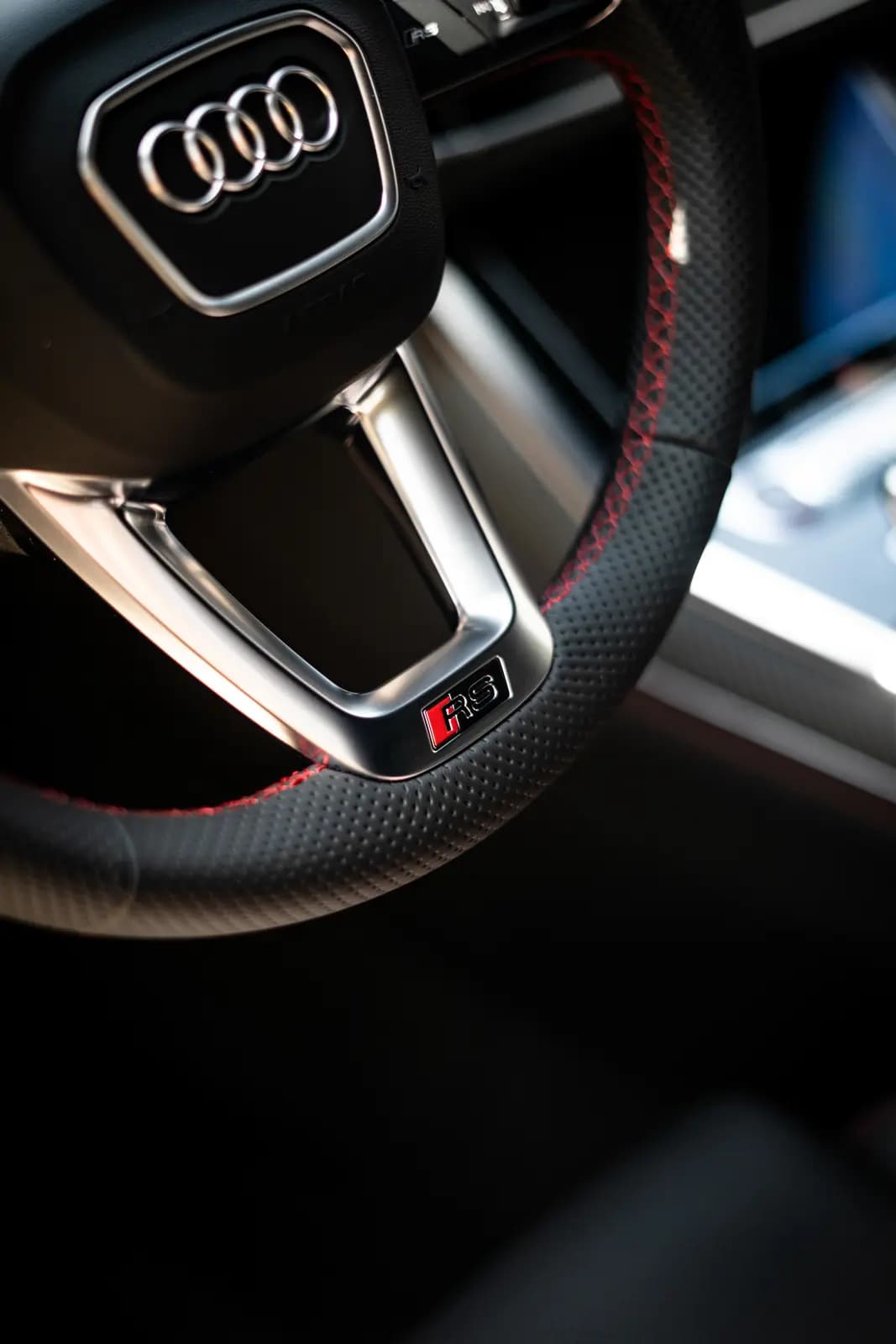 Steering wheel with the Audi four rings and a red-and-black “RS” badge.