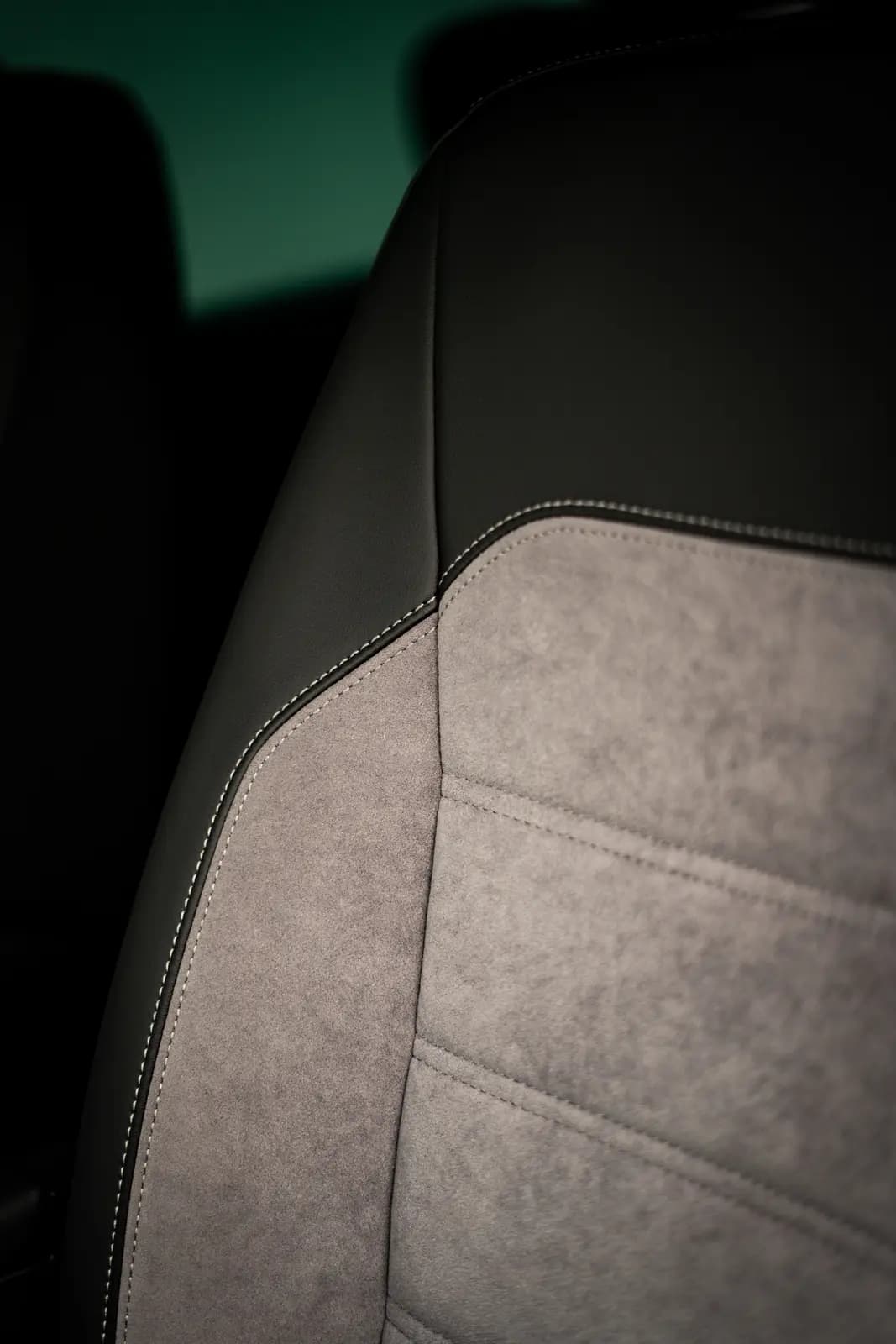 Seat in black leather with a grey Alcantara insert and contrasting white stitching.