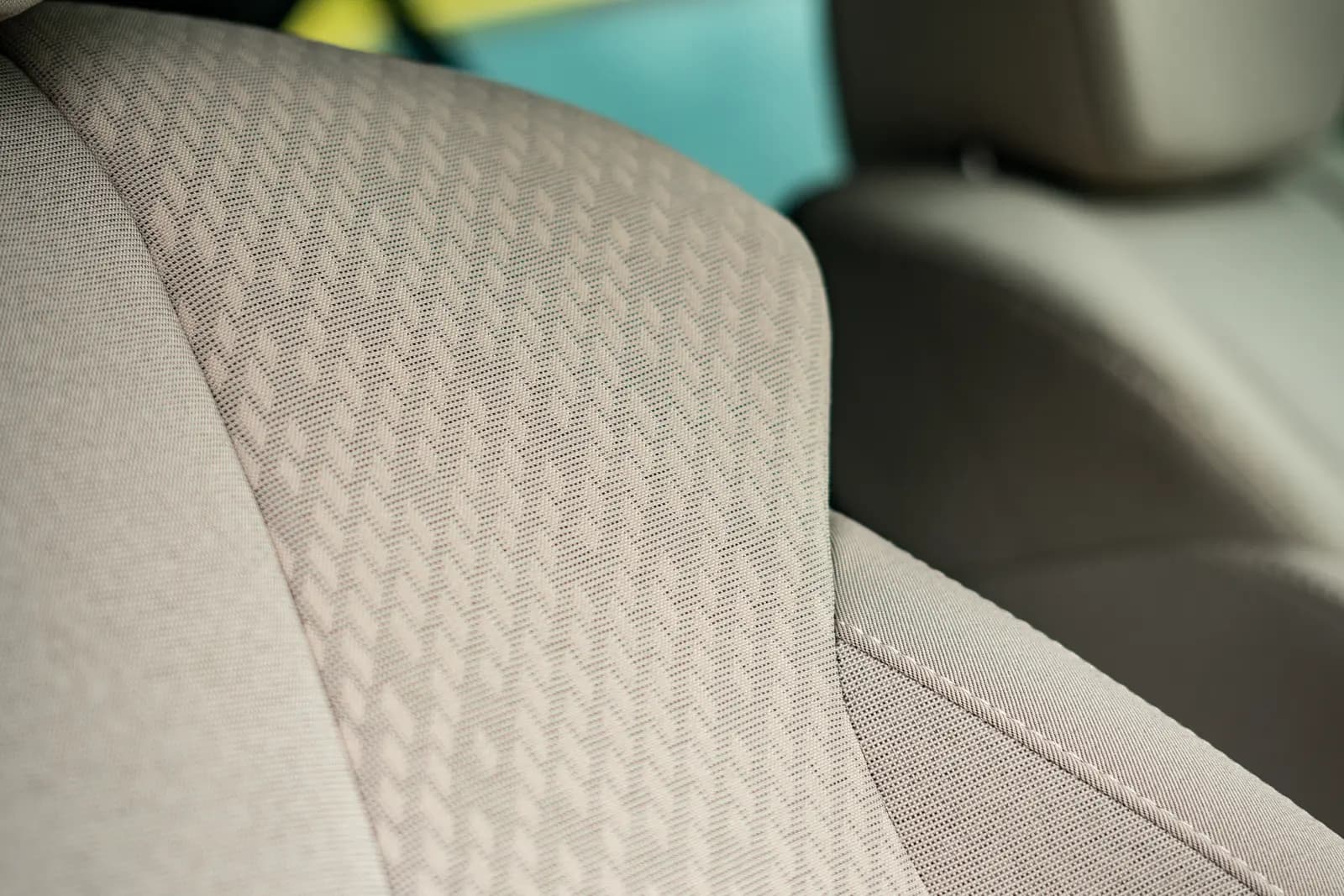Fabric seat back with a patterned weave and white stitching along the edge.