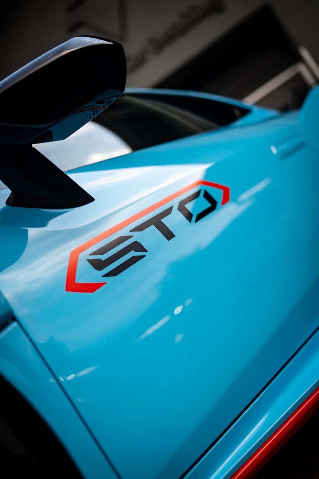 Side of a light blue car with an applied “STO” graphic in red and black and a black door mirror.